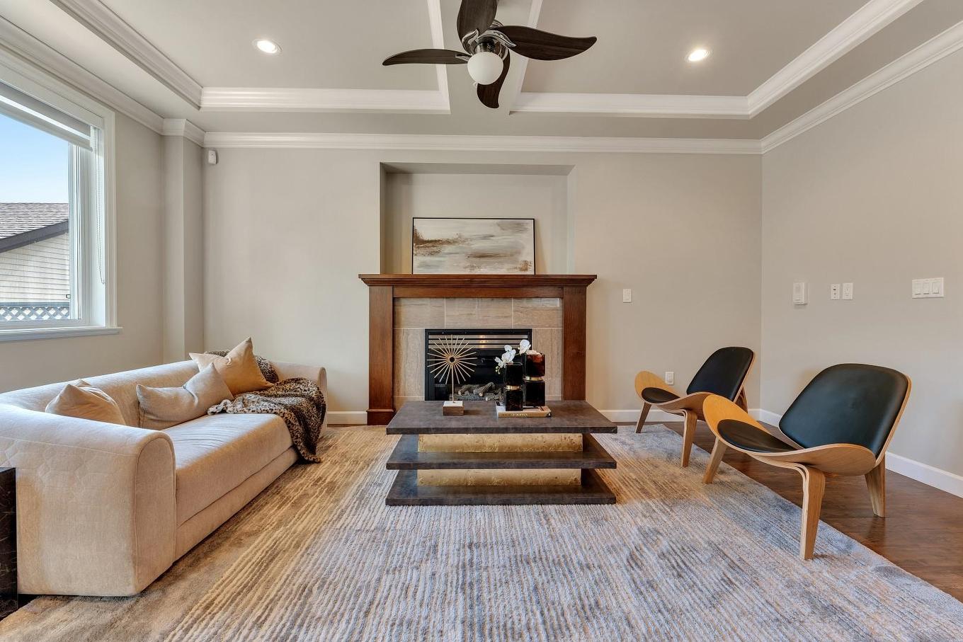 Modern living room featuring a light sofa, wooden fireplace, armchair, and a light area rug. Bright atmosphere.