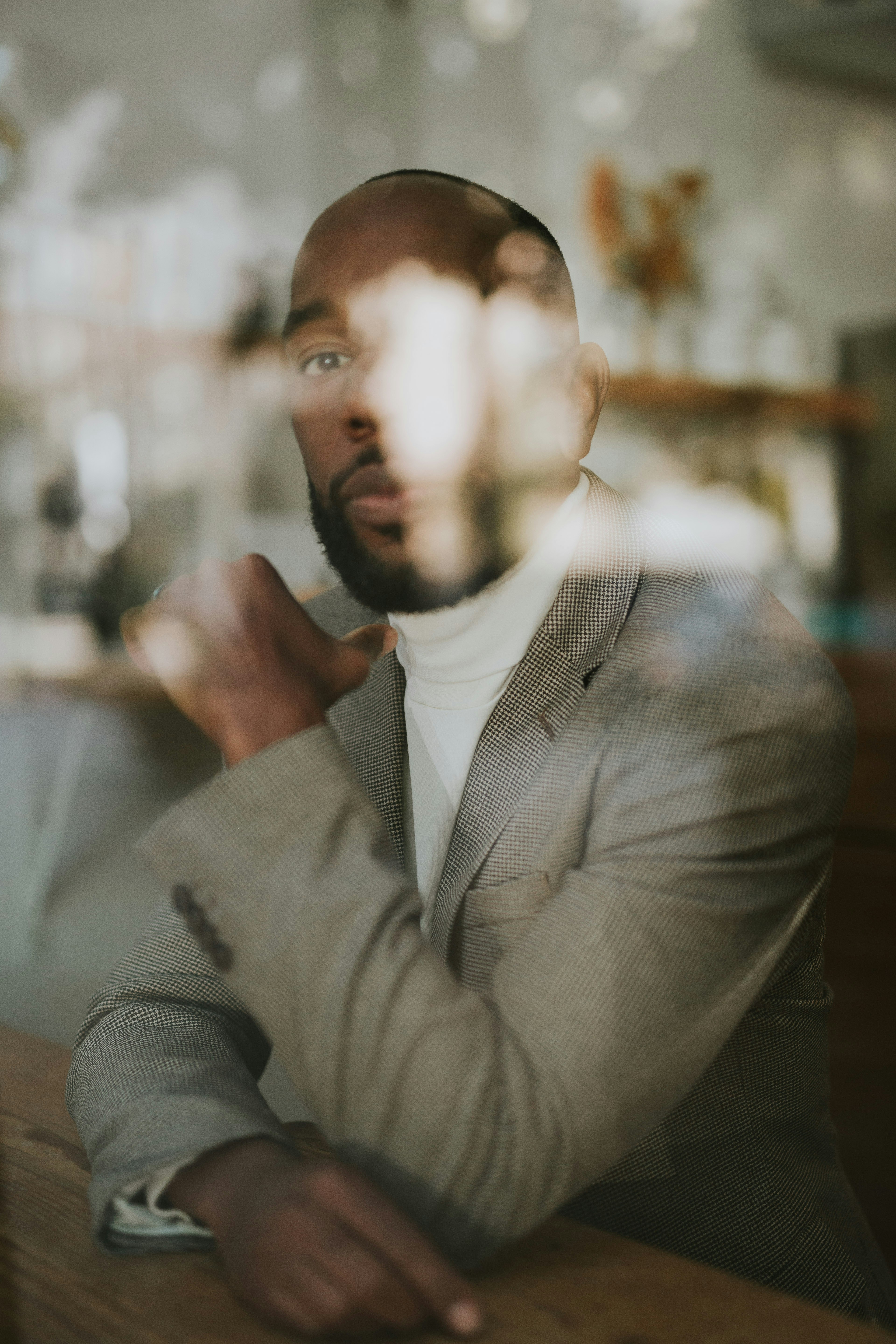 A man is sitting and holding a phone, partially obscured by a blurred background.