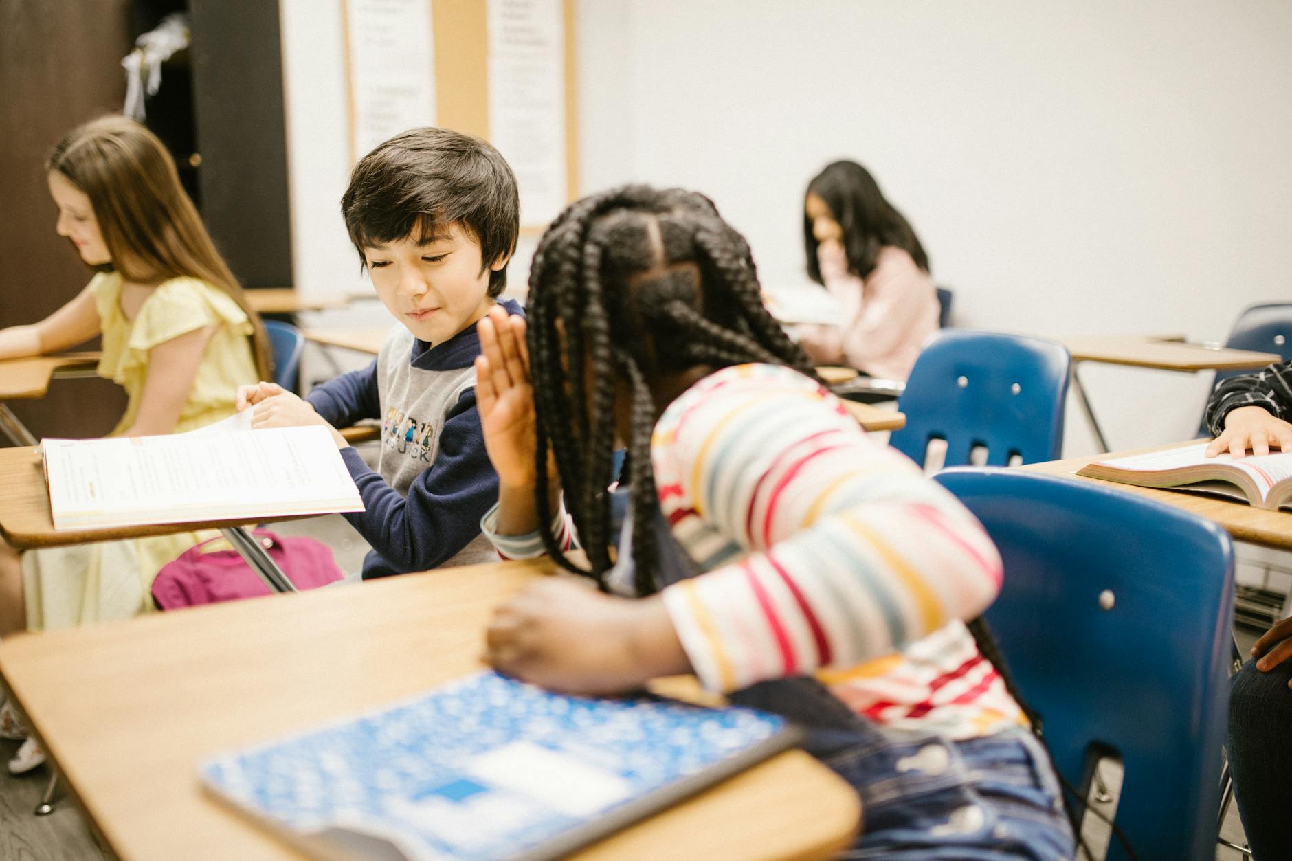 Diverse students sitting in a circle on a rug, actively listening and gesturing during a group discussion.