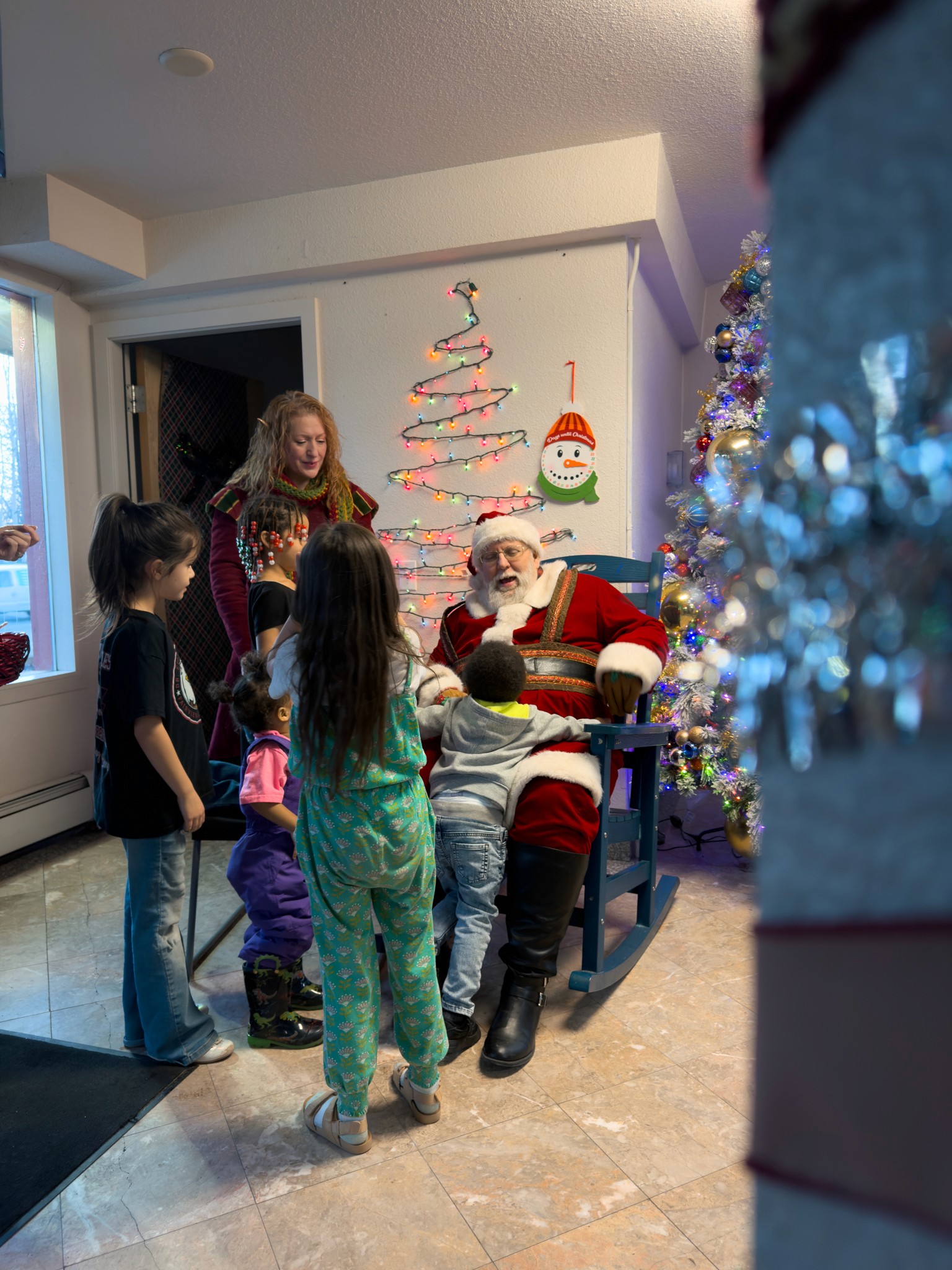 Modern home office setup with a monitor, ergonomic chair, keyboard, and indoor plants near a window with blinds.