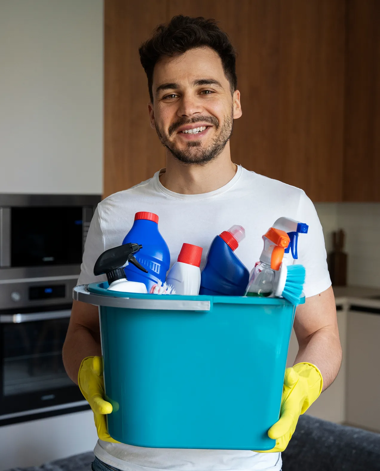 Senior Cleaner Latham Smith smiling while holding a bucket filled with various cleaning detergent bottles, showcasing 4 years of professional experience.