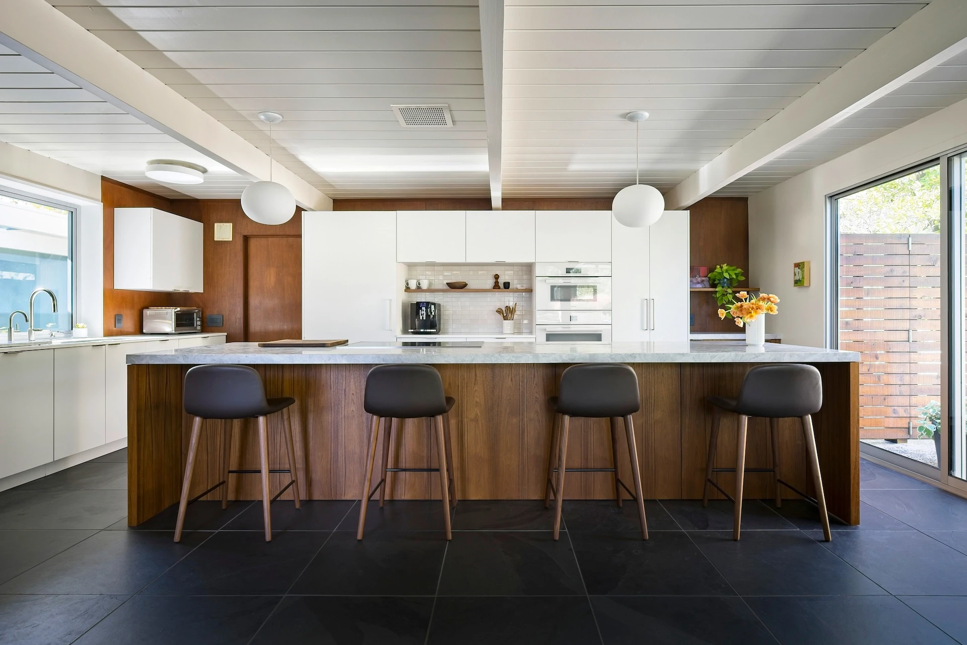 Wide shot of the entire kitchen and island, facing the oven wall, illustrating the harmonious blend of modern appliances and timeless Eichler design. Photo by Todd Huge.