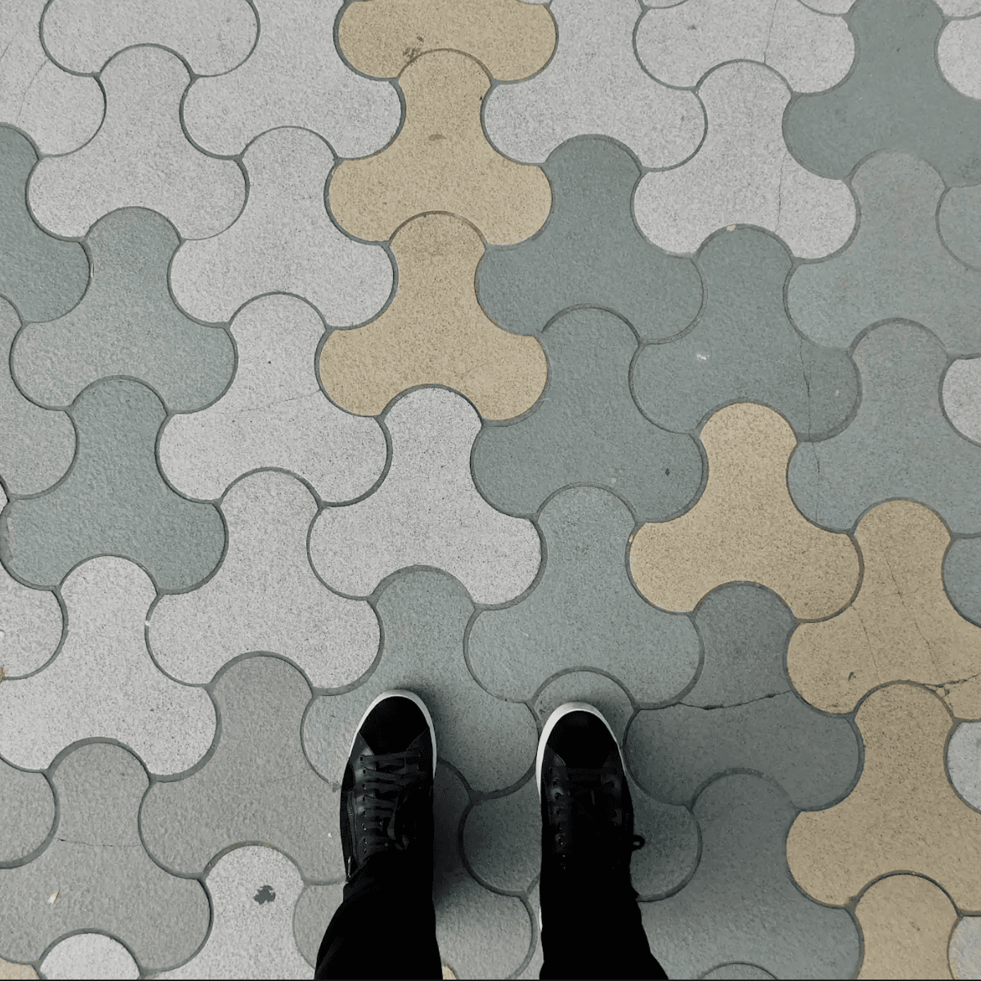 Shoes standing on interlocking paver blocks, location unknown.