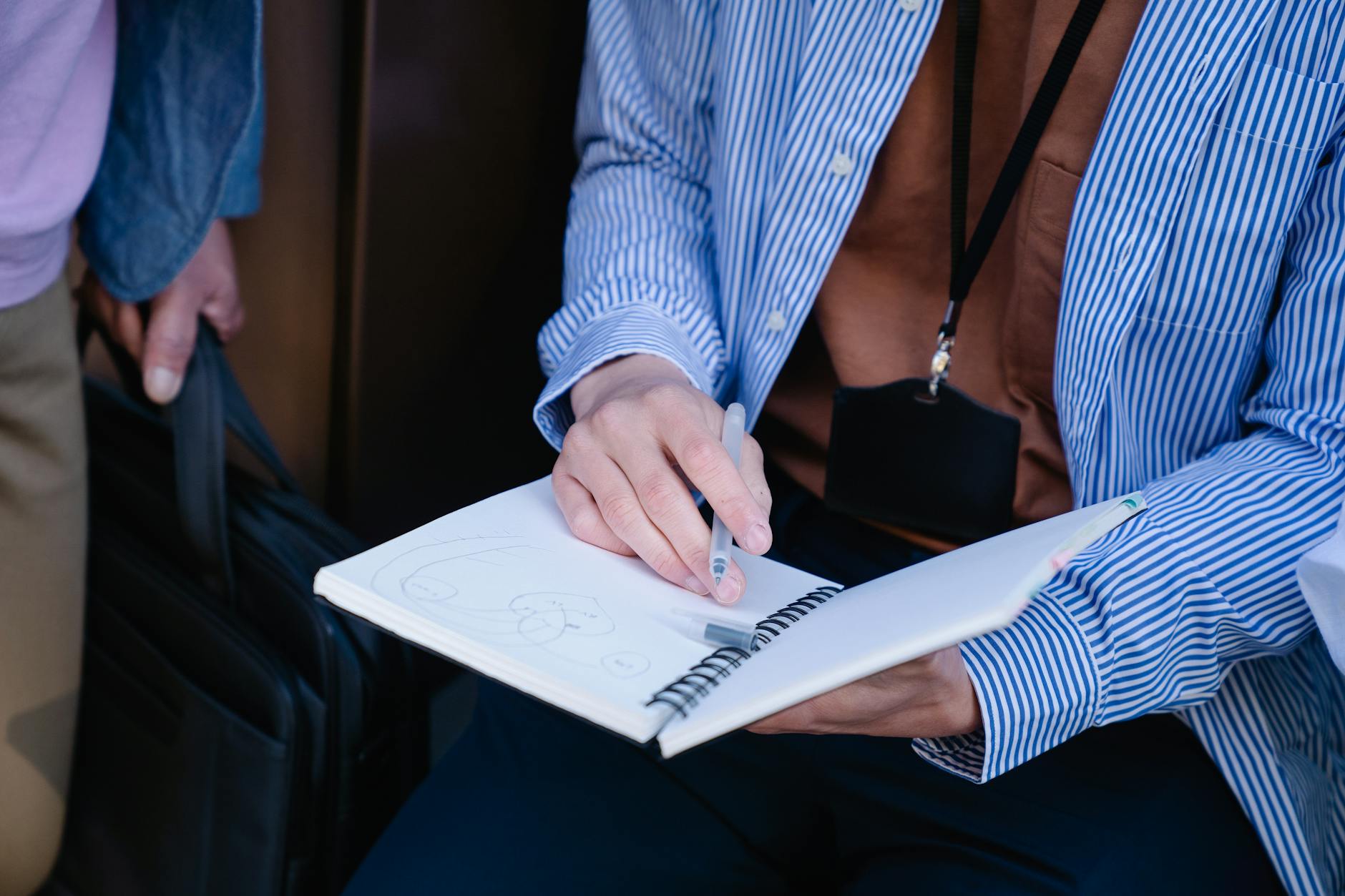 Close-up of a teacher's hand marking a tally sheet next to a laptop during a self-audit of lesson delivery.