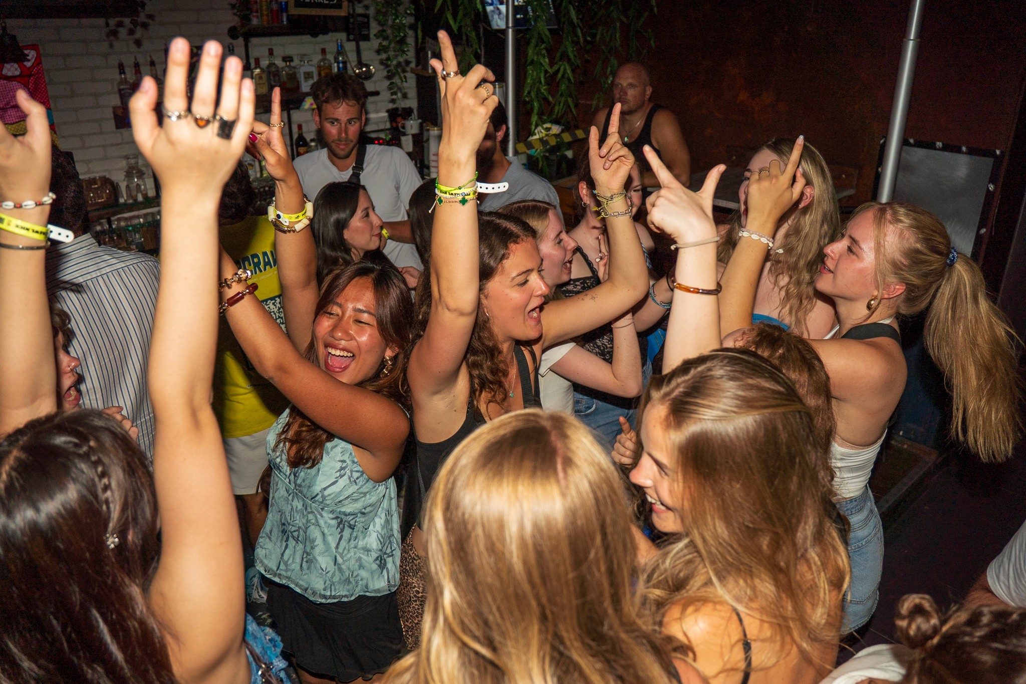 Group of travelers raising their hands and dancing together during an icebreaker activity on a pub crawl in Nice creating high energy social nightlife moments in the French Riviera