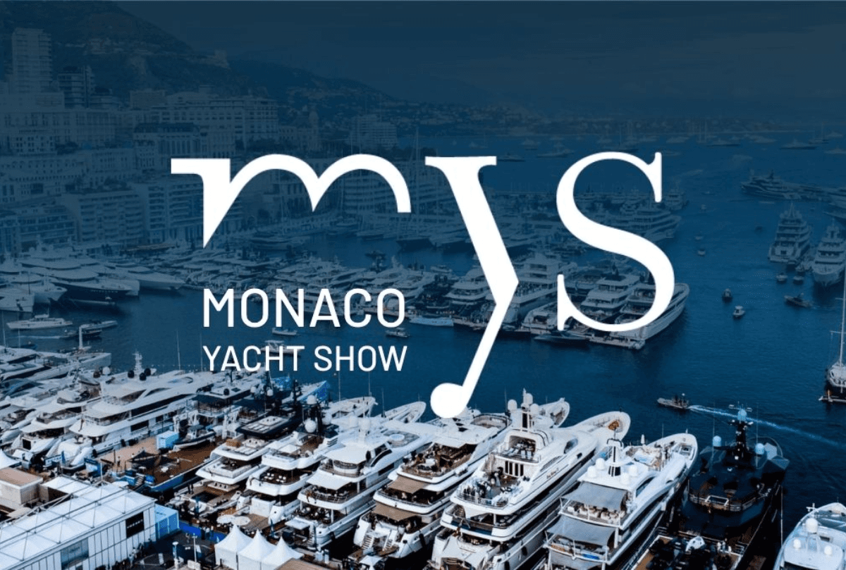 A person working on their home office desk with their headphones on. The lighting is dark with subtle,soft lights coming from a lamp