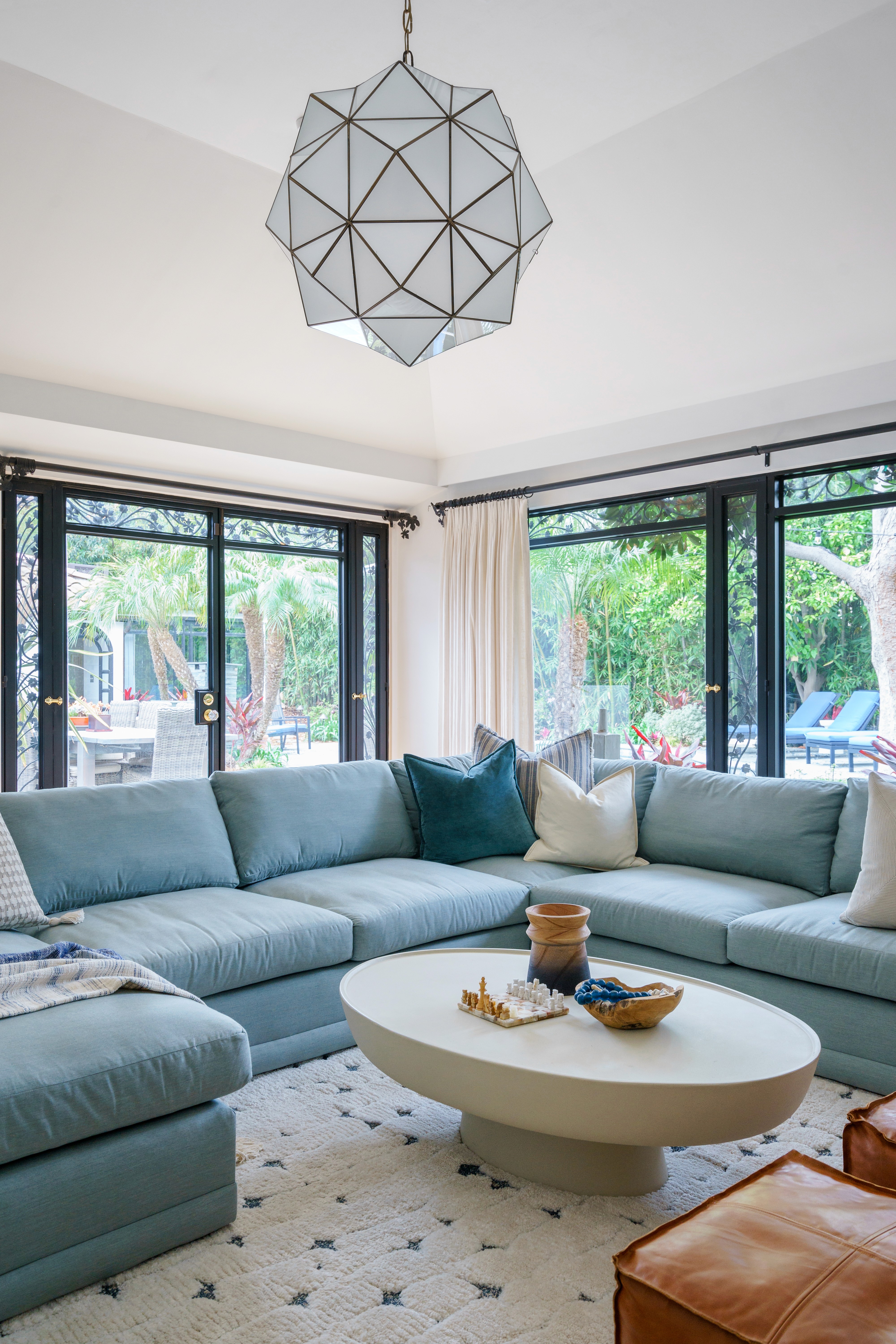 This outdoor oasis blends natural charm and refined luxury with a studded stone side table, linen accents, a sleek sun bed, large umbrella, and slate-inspired tiles, creating a harmonious sanctuary