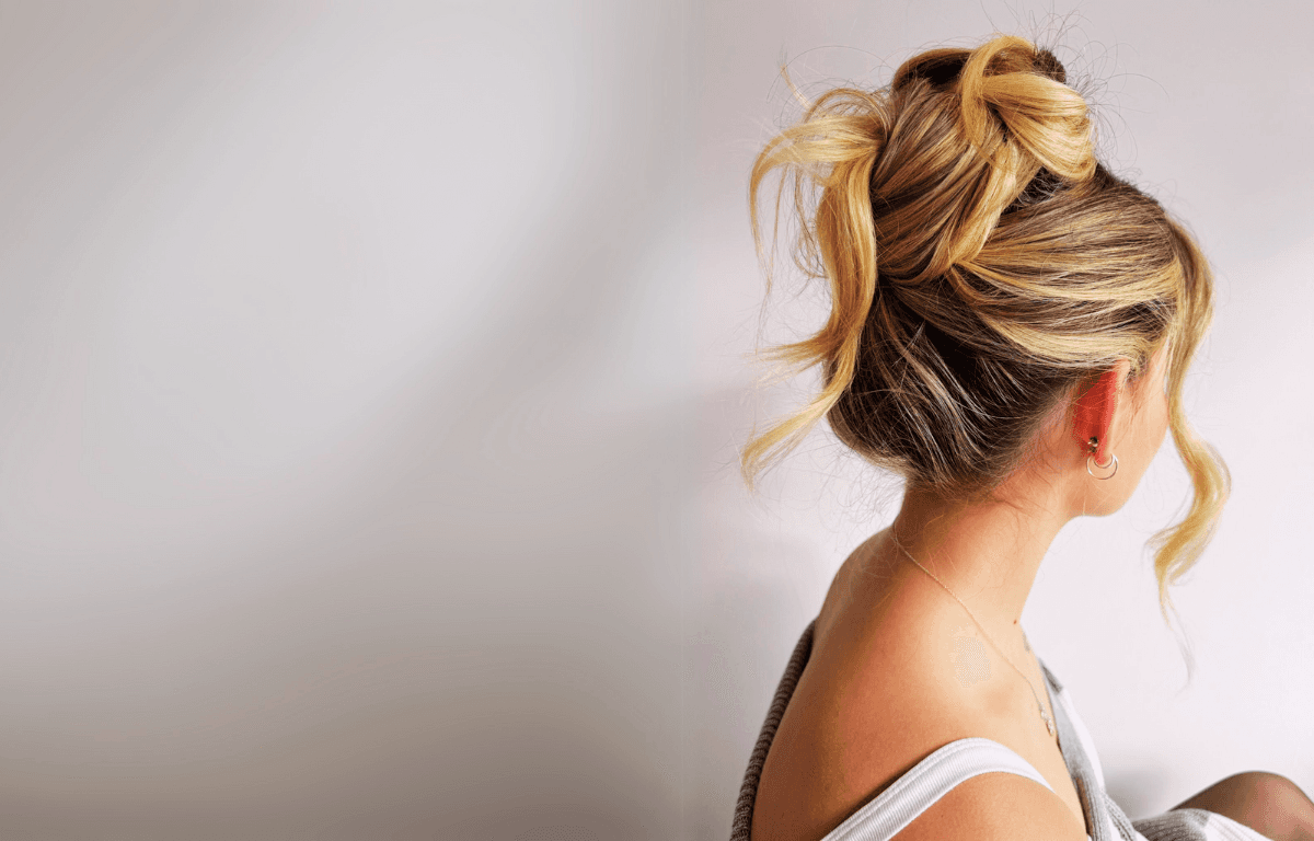 Woman with blonde hair tied up into a messy bun