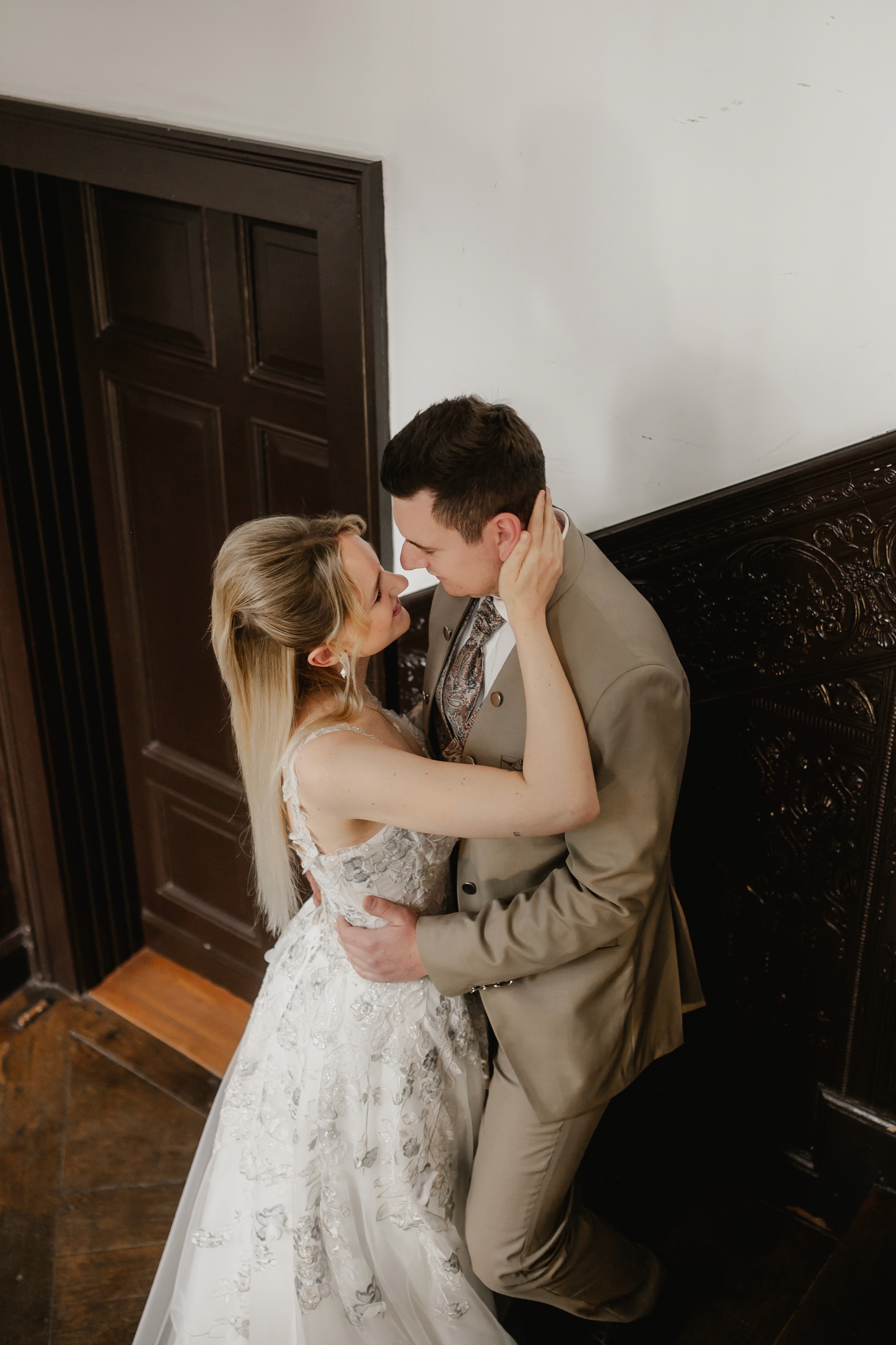 Brautpaar umarmt sich innig auf einer Treppe, die Braut trägt ein Spitzenkleid