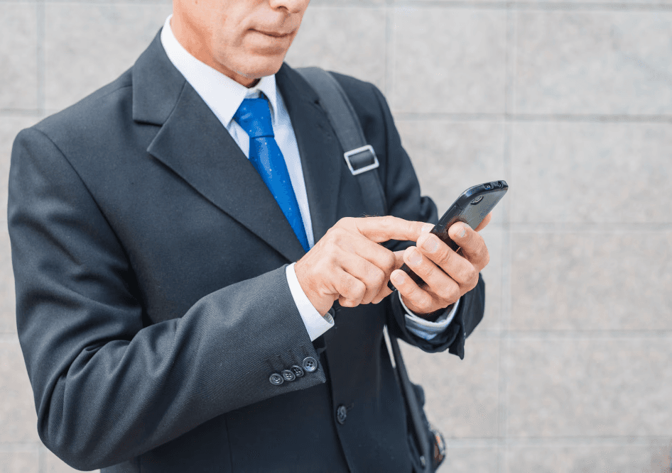 Executive holding his phone and checking the HoustonPlus app.