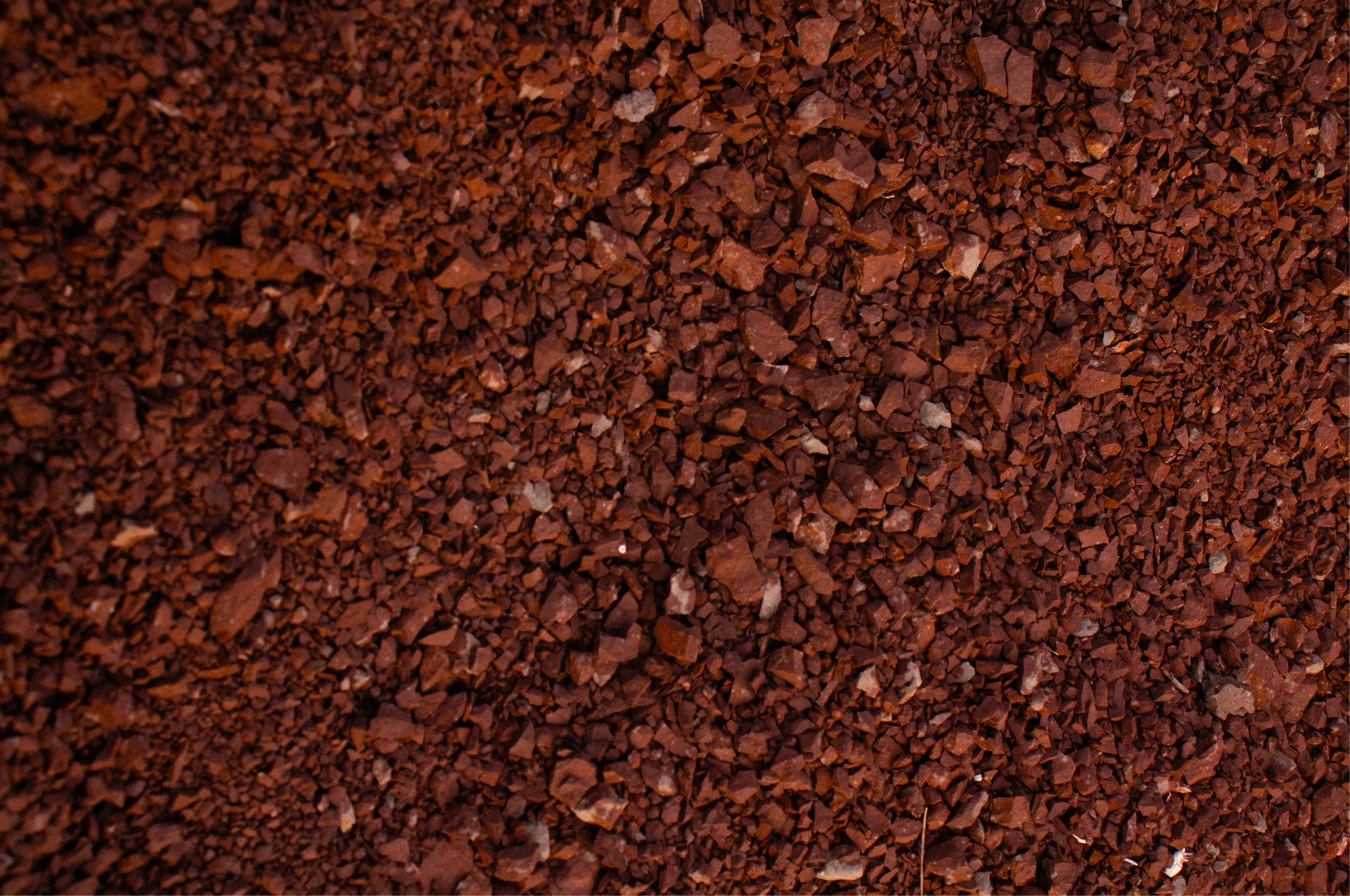 Abstract close-up of red gravel and small mineral fragments, used as a texture and atmosphere image.