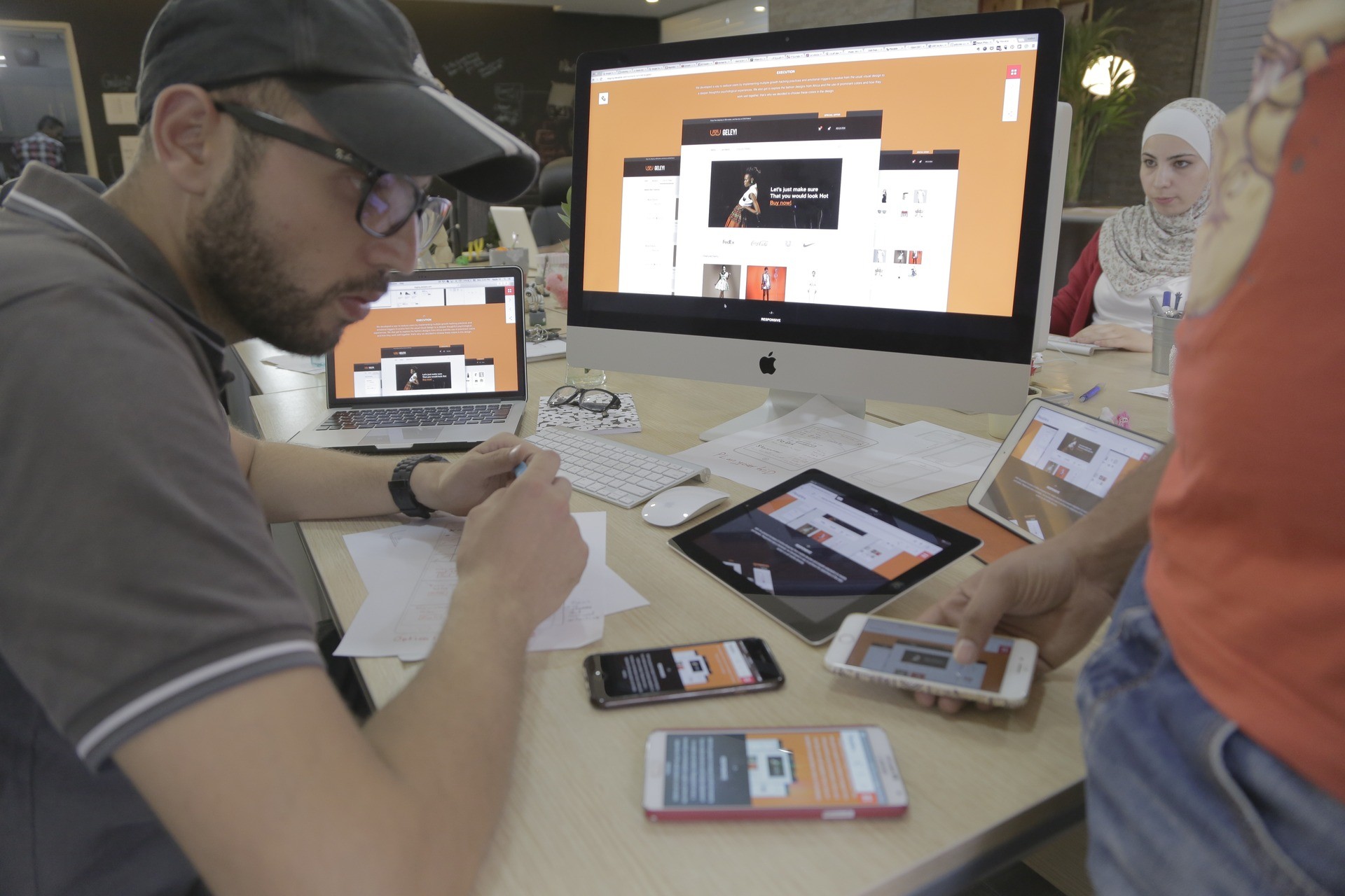 Team reviewing a responsive interface across desktop, tablet, and mobile devices