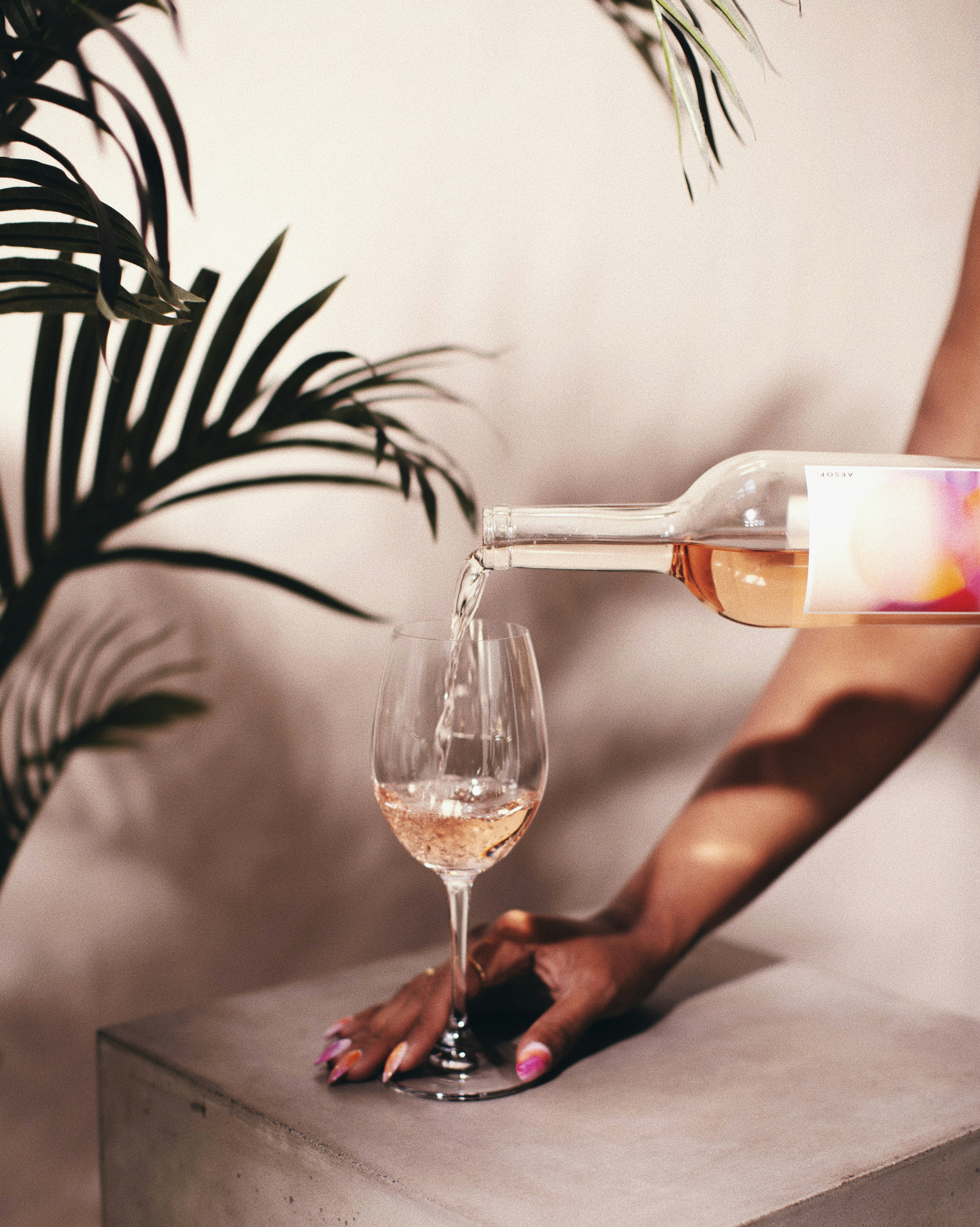 brown woman pouring rose wine in a glass