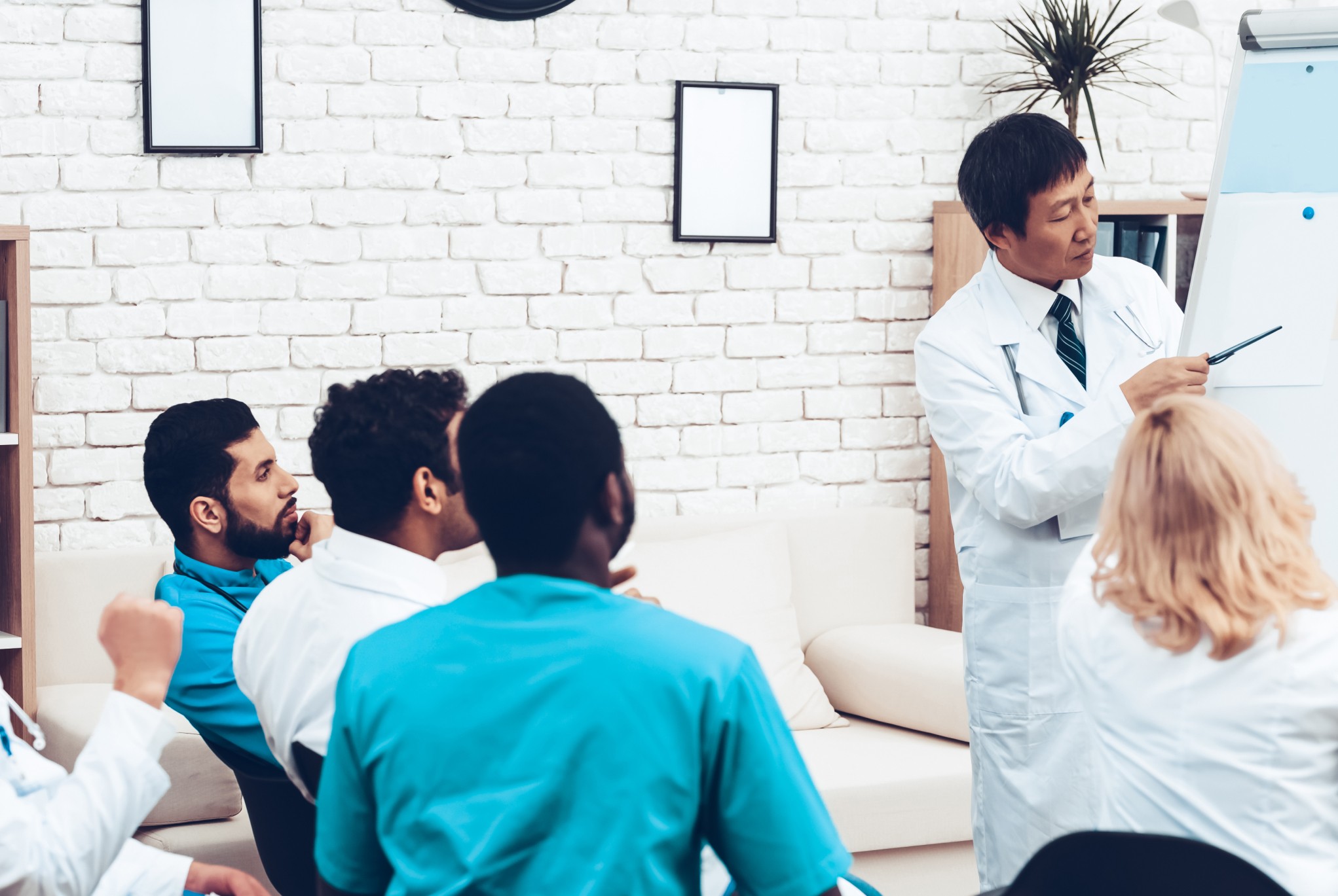 A group of healthcare professionals in a training session, led by a senior doctor presenting strategies for improving revenue cycle management on a whiteboard.