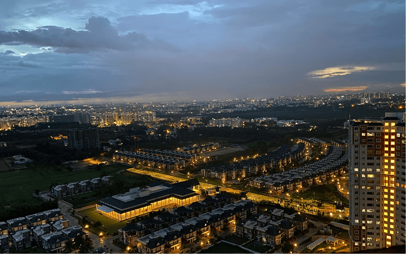 Image of the Bangalore city skyline at dusk with illuminated buildings and streets.
