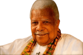 Color portrait of an elderly man with short, white hair and a warm smile. He wears a white traditional shirt paired with a colorful kente cloth scarf, suggesting cultural pride and heritage. His expression is gentle and welcoming, exuding wisdom and warmth.