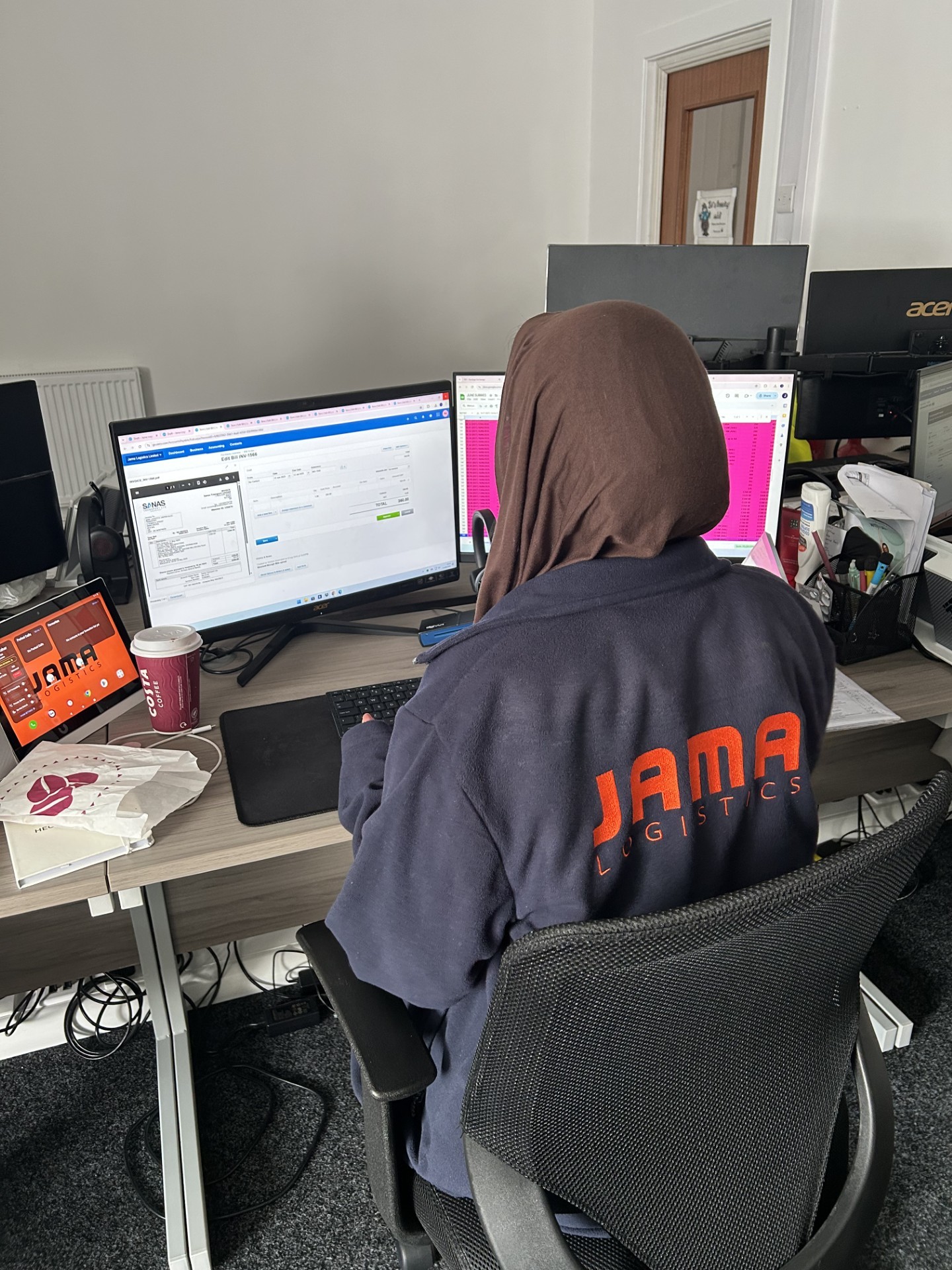 image of the back of a person looking at two monitors in an office
