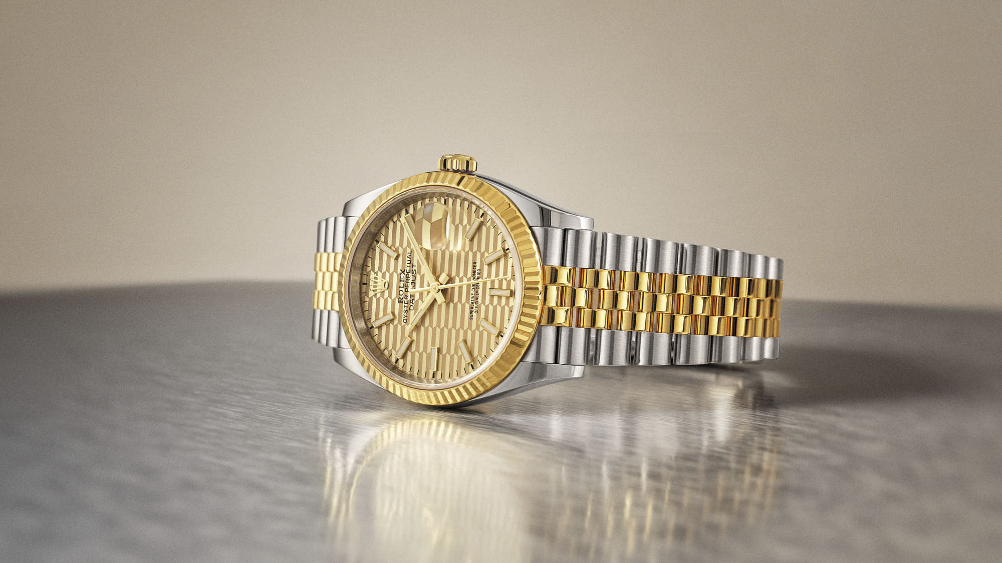 A gold and silver rolex watch resting on a reflective surface, showcasing intricate detailing and a shiny finish.