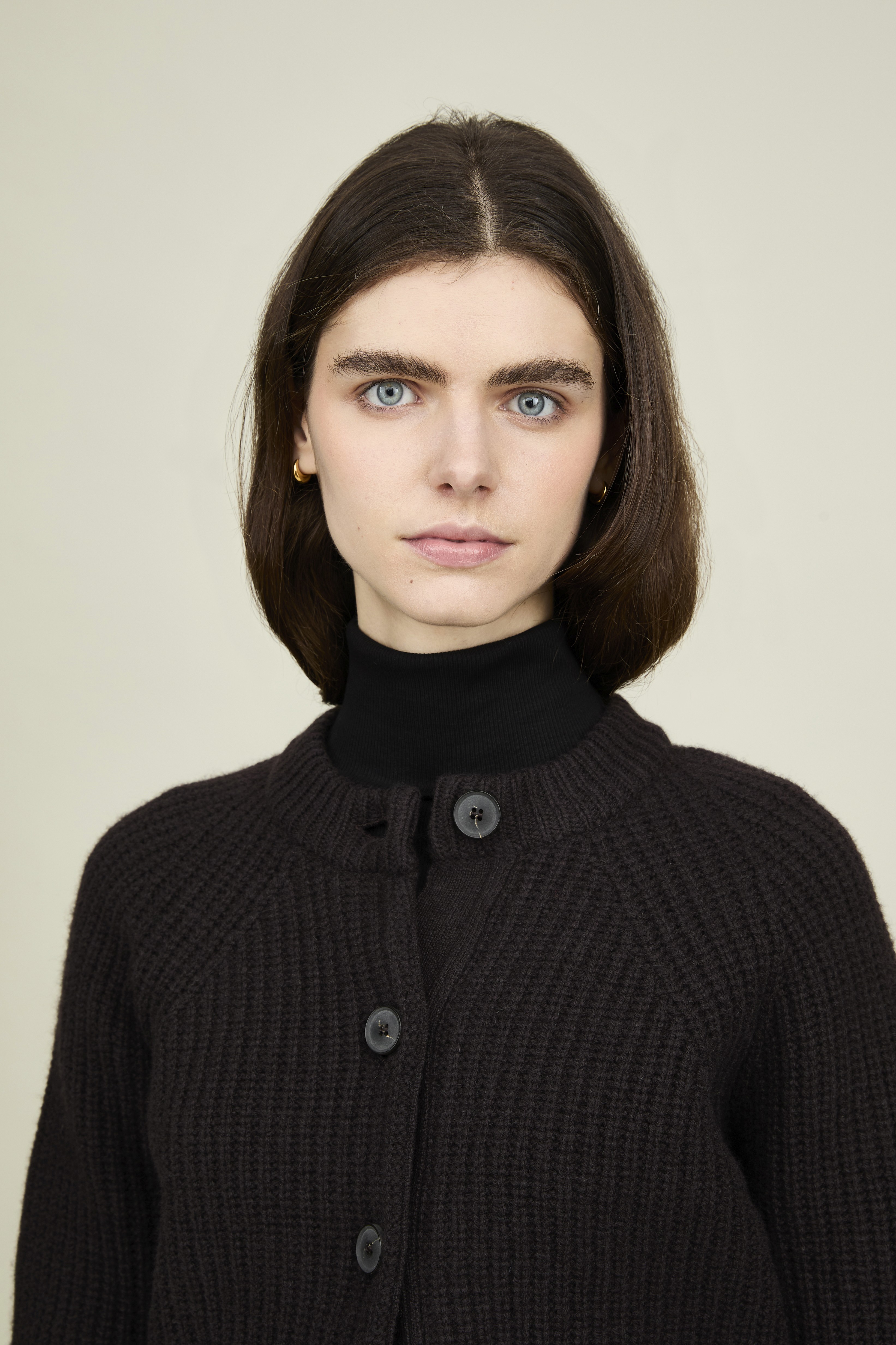 Une femme porte un cardigan noir Sunspel