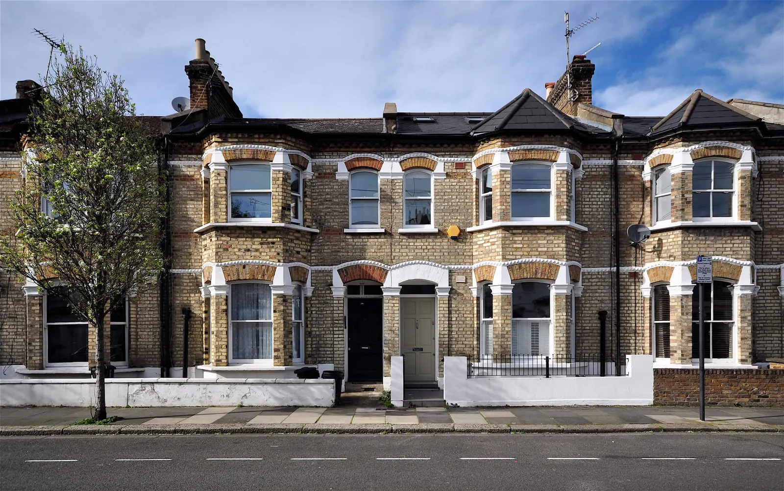 A row of Victorian terraced houses with bay windows on a residential street.