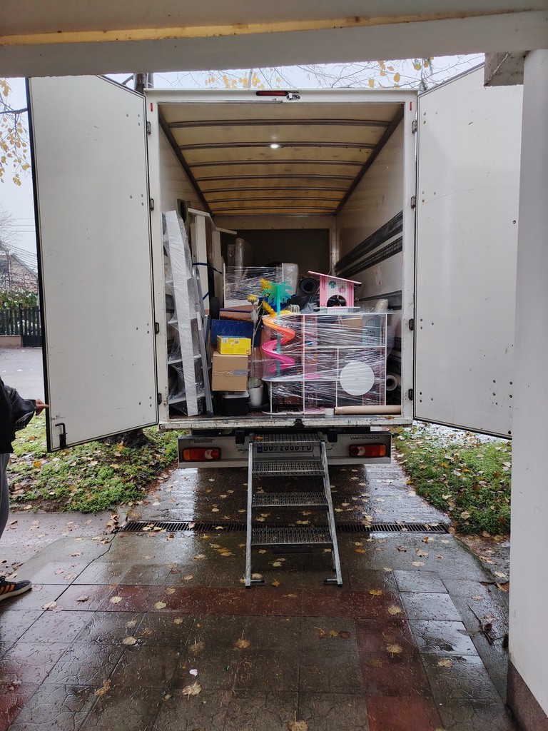 Teretni kamion napunjen nameštajem i kutijama, vrata otvorena i stepenice postavljene.