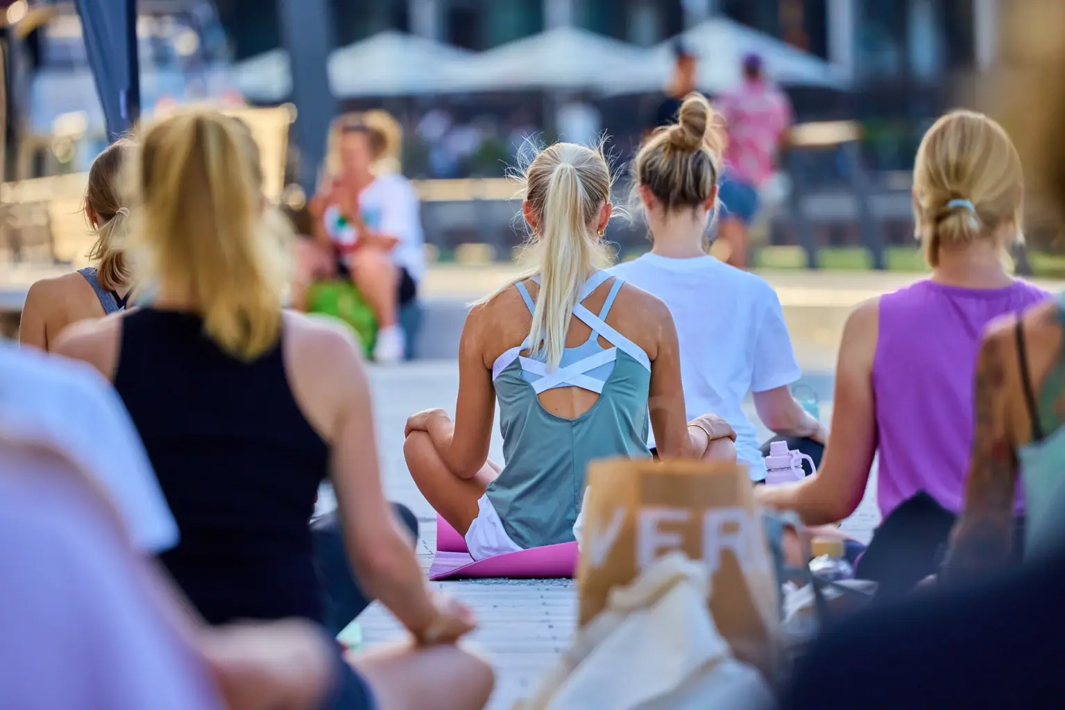 Menschen praktizieren Yoga bei einem Picknick am Dranländersee, entspannen in der Natur und genießen gesunde Snacks – ein Event von Strong Partners im Bereich Betriebliches Gesundheitsmanagement.