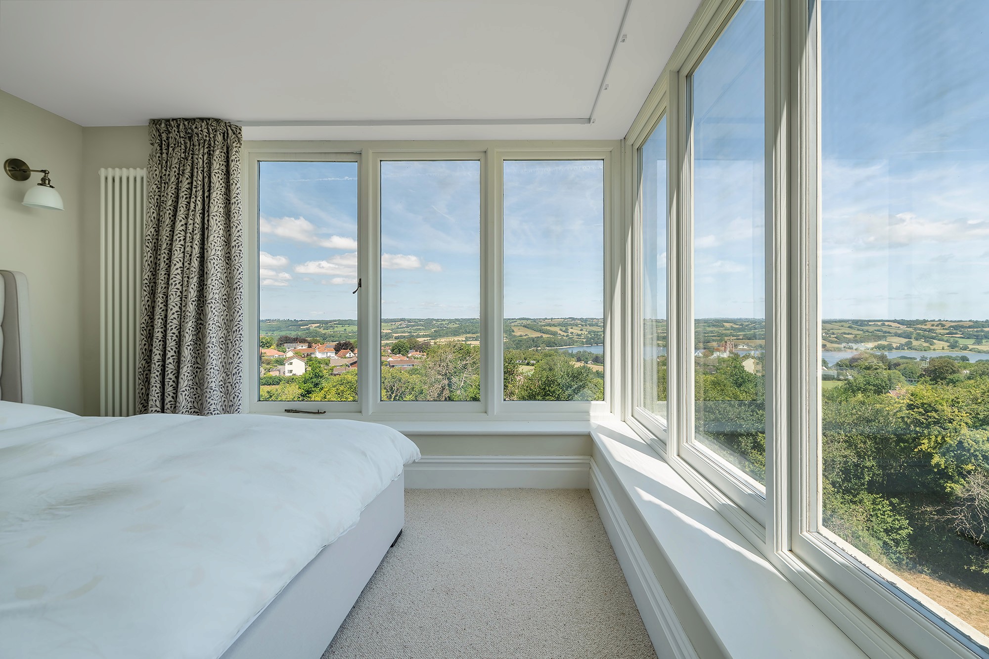 Principal bedroom with corner glazing and countryside-to-lake views in daylight