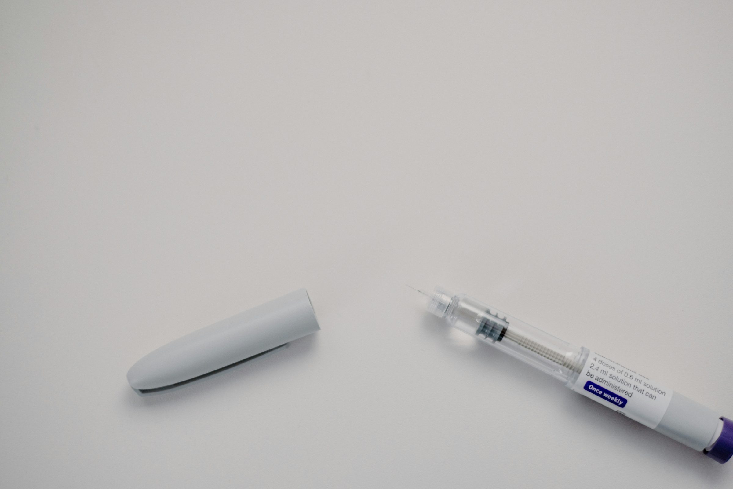A GLP-1 injection pen with its cap removed on a white surface