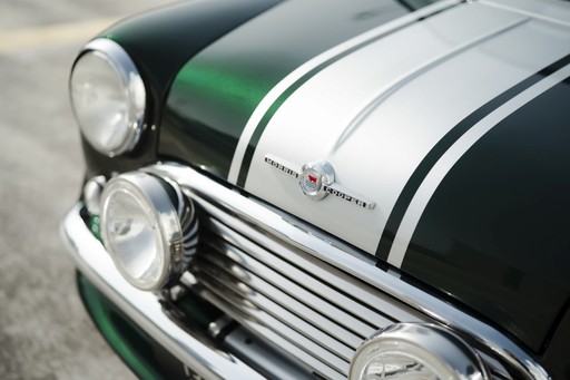 Een close-up van de grille van een vintage groene auto, compleet met zilveren strepen en van die klassieke ronde koplampen.