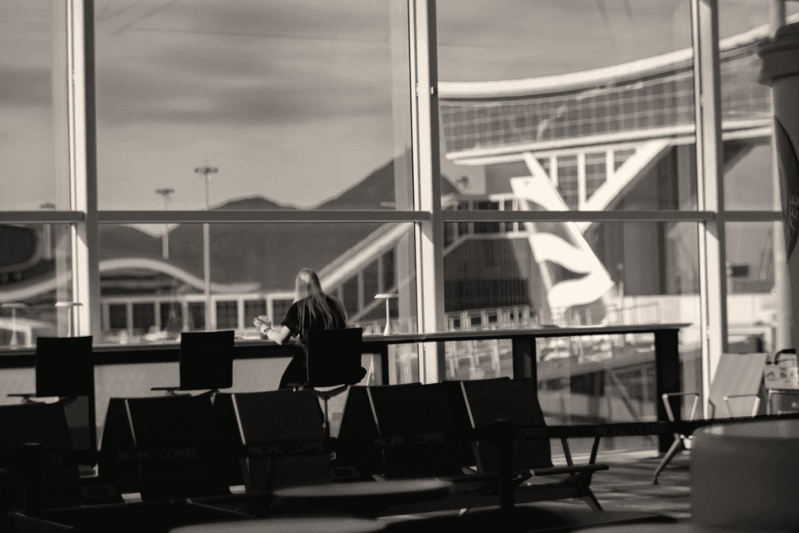 a woman sitting at an airport terminal looking at her cell phone