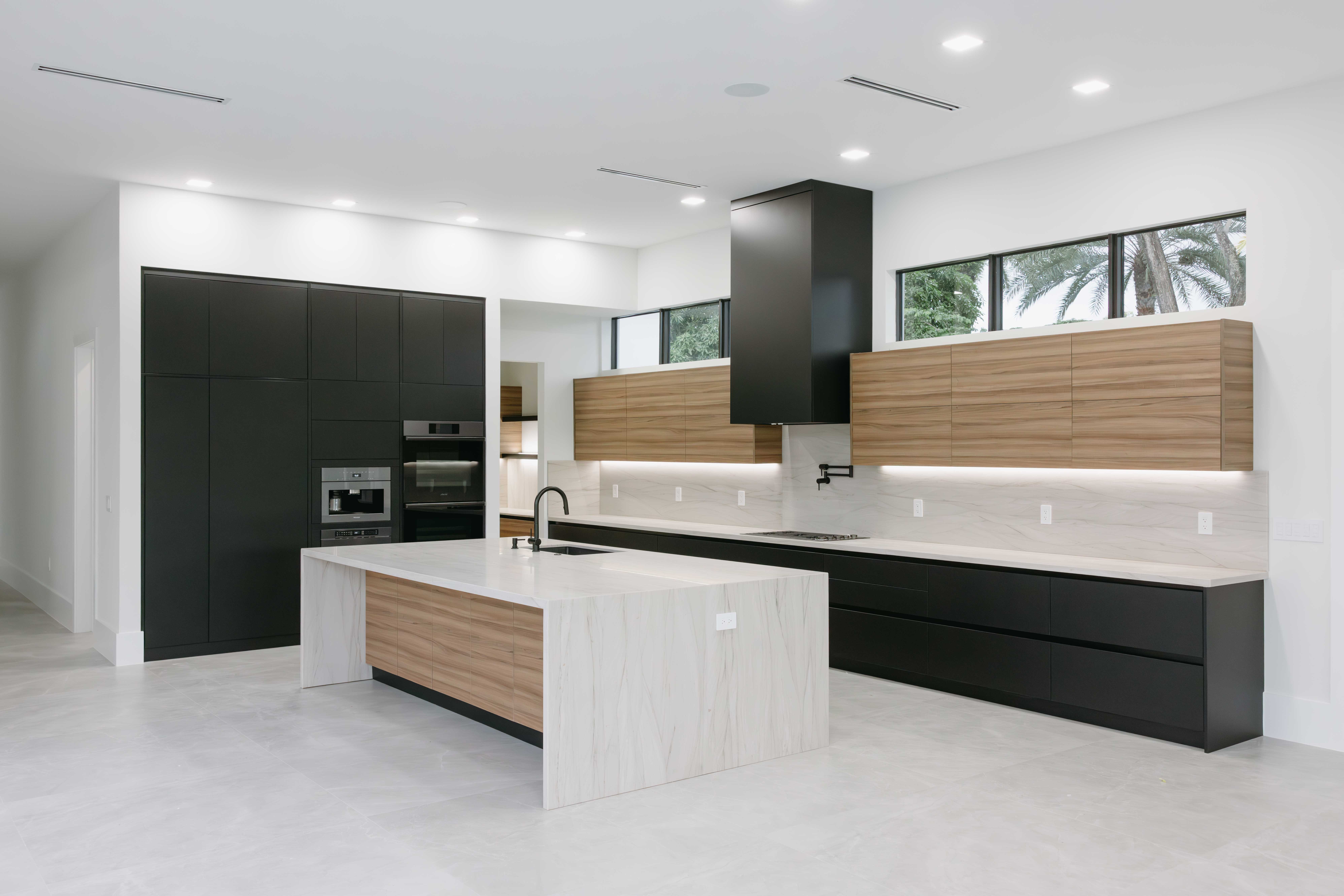 Modern black and wood kitchen with large island and black range hood.