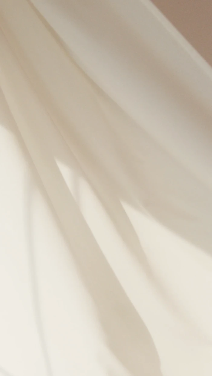 Intricate folds of beige silk satin material, highlighting the premium drape and feminine elegance of high-end evening wear.