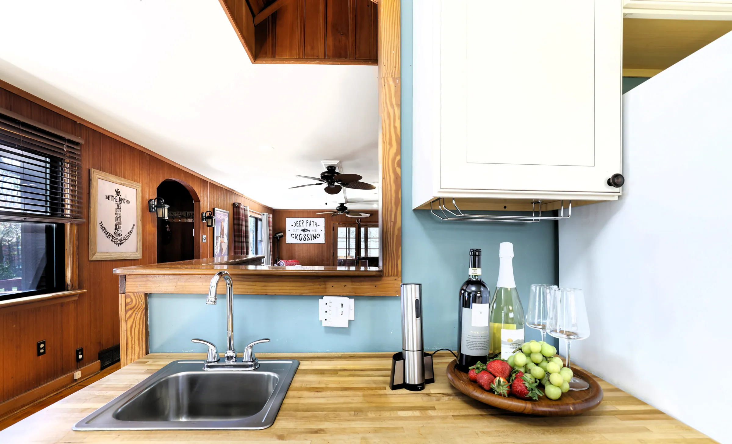 Butcher block counter with sink, wine glasses and pass-through to the living room at DeerPath Crossing