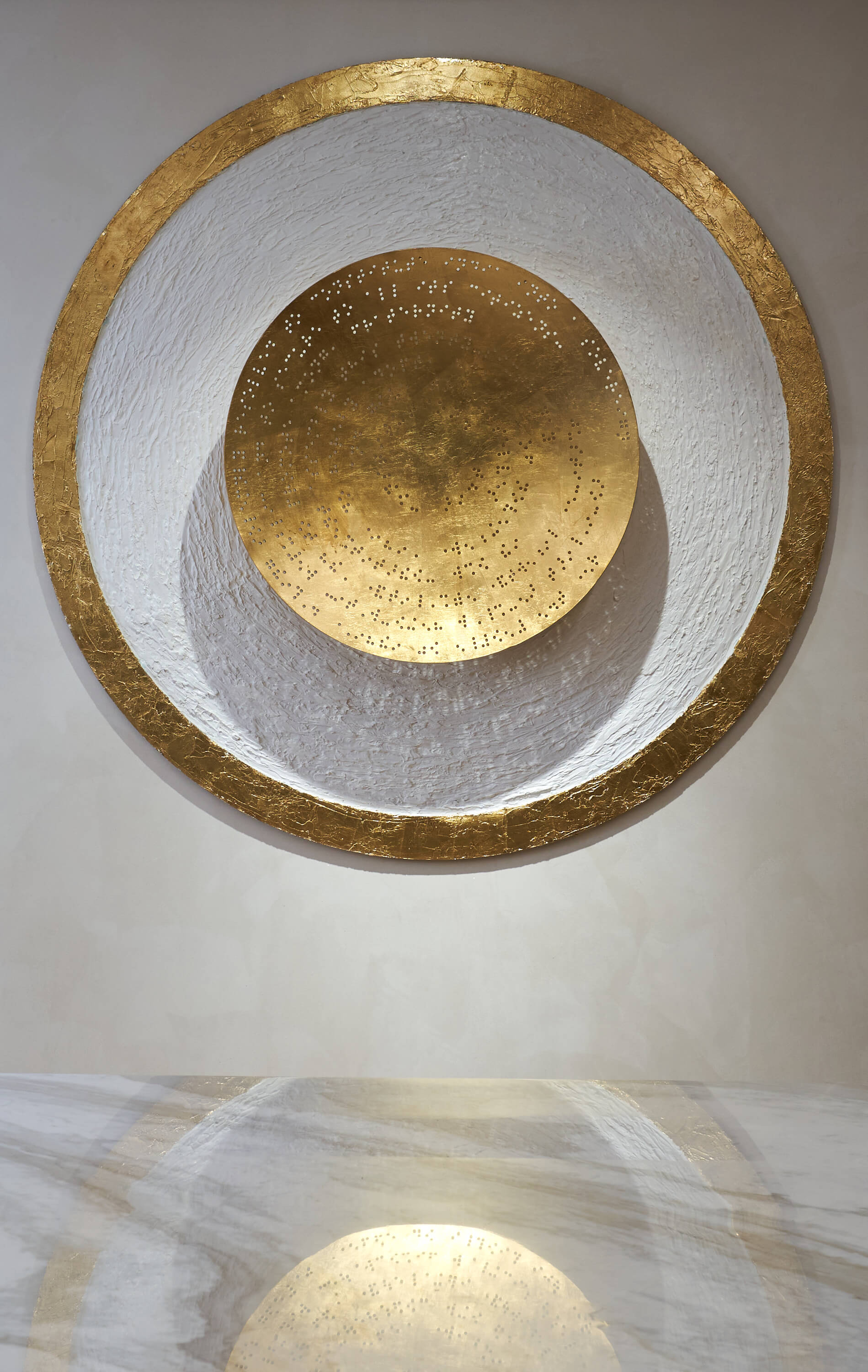 Close-up of textured circular gold and white statement wall installation.