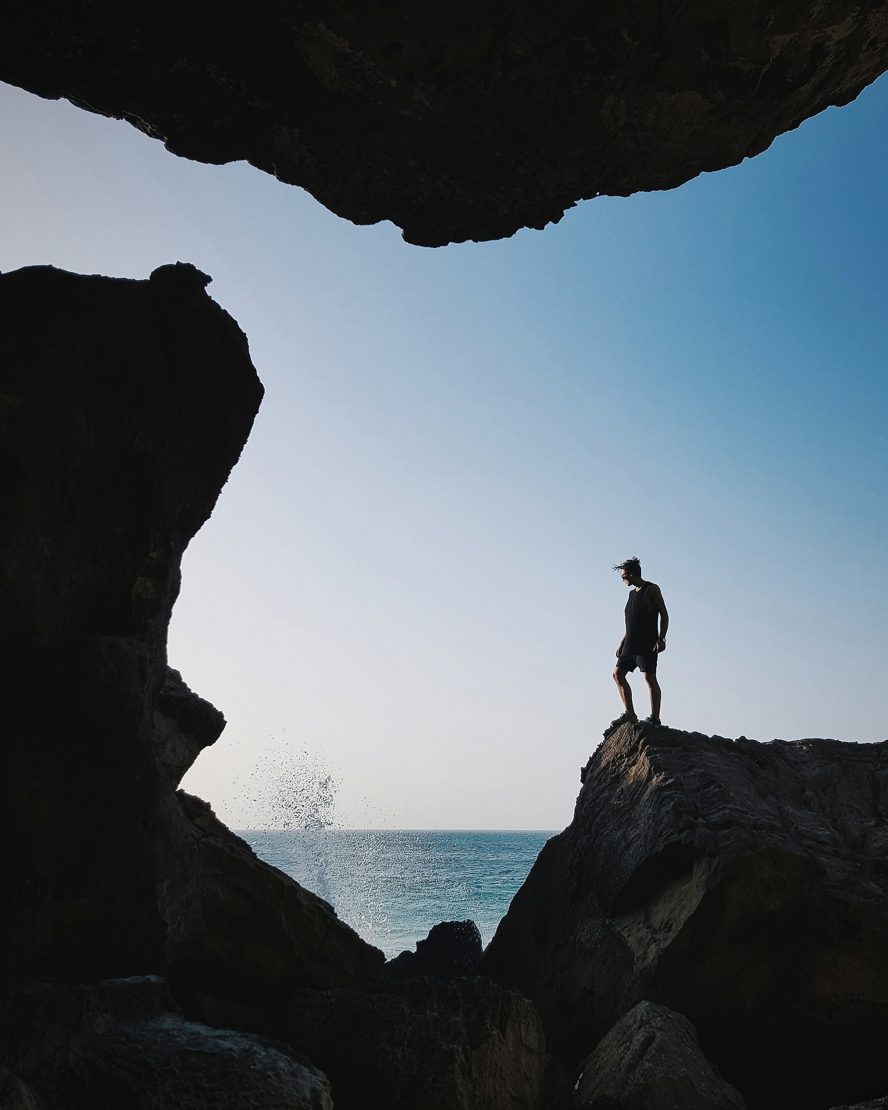 Silhouette of man looking at a difficult climbing situation with a sea view in the background on a sunny day