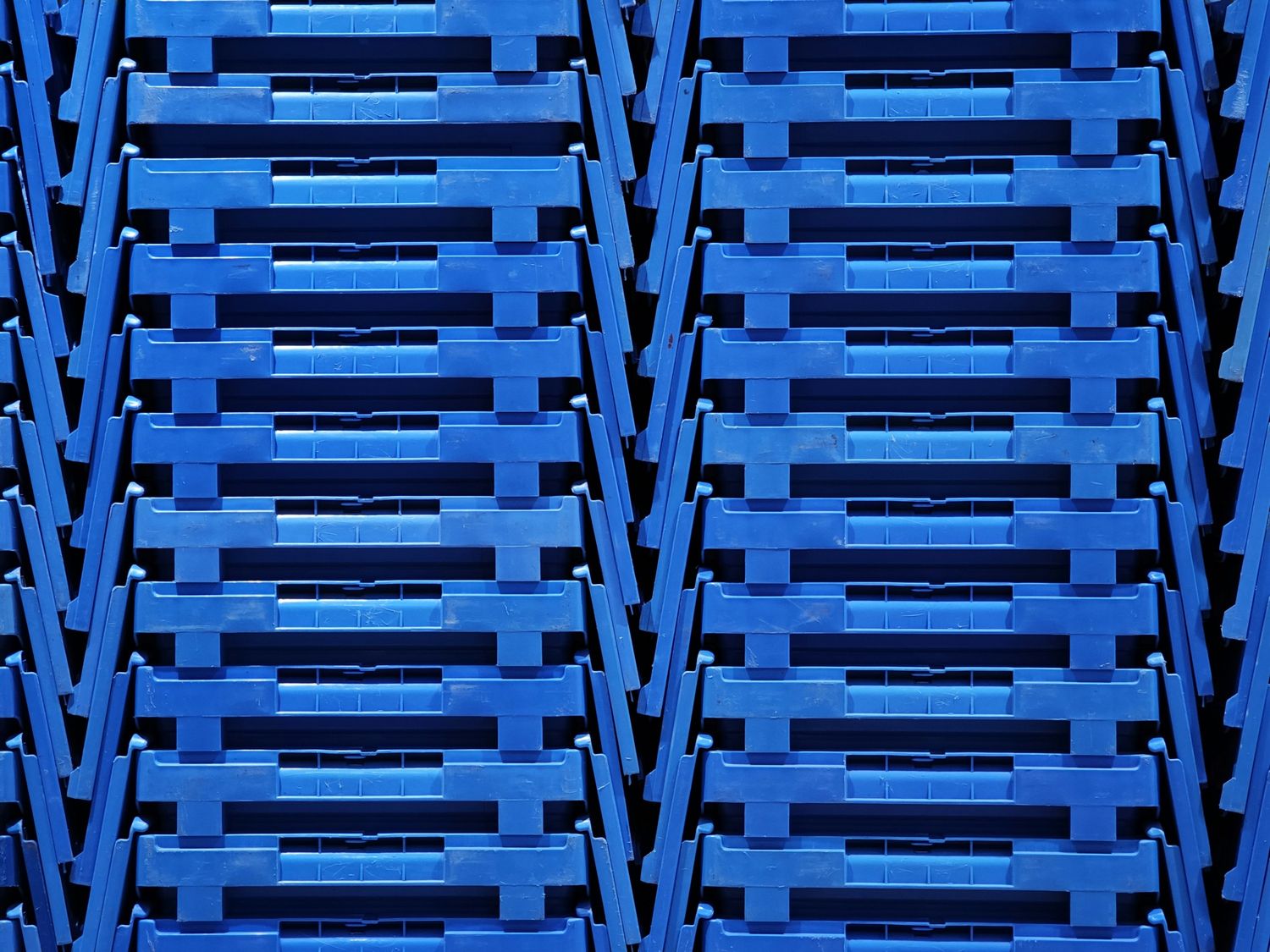 Stacked blue plastic crates form a geometric pattern. The vibrant colour conveys a clean and industrial feel.