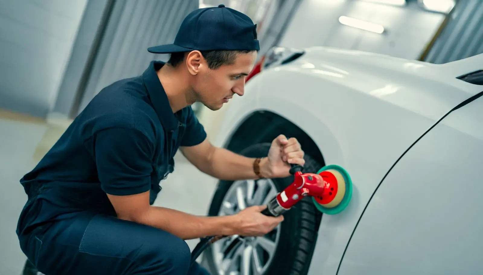 Auto technician polishing out surface scratches to restore a smooth, flawless vehicle finish.