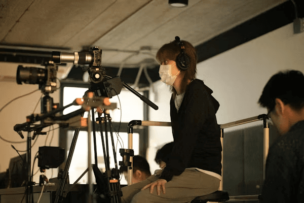 High school student conducting media studies research with a PhD mentor reviewing academic work on a laptop