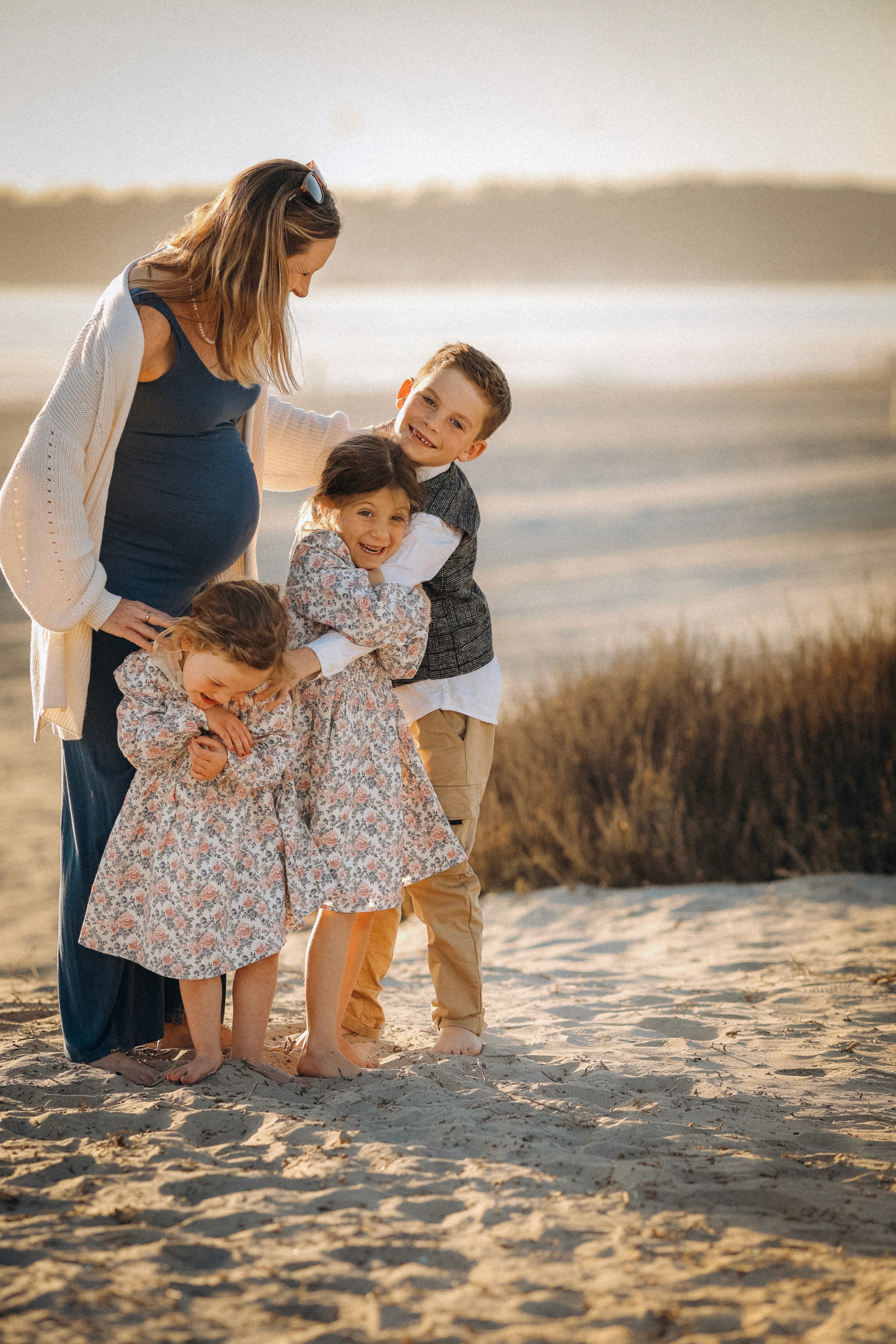 Young girls laughing in warm evening light during a relaxed family photo session.