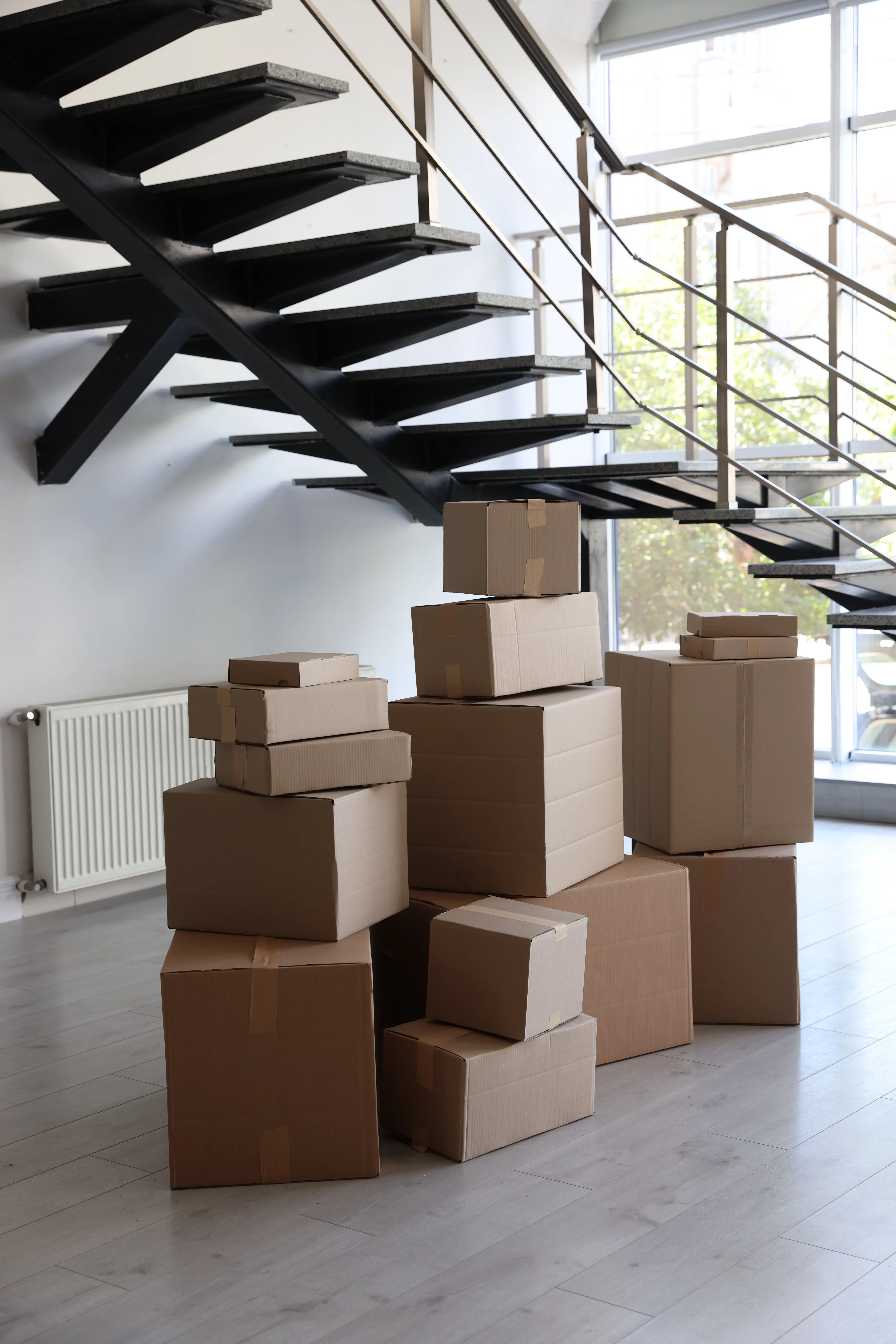 Stacks of packed cardboard moving boxes inside a home foyer, illustrating common workplace relocation fraud scenarios under California Labor Code Section 970