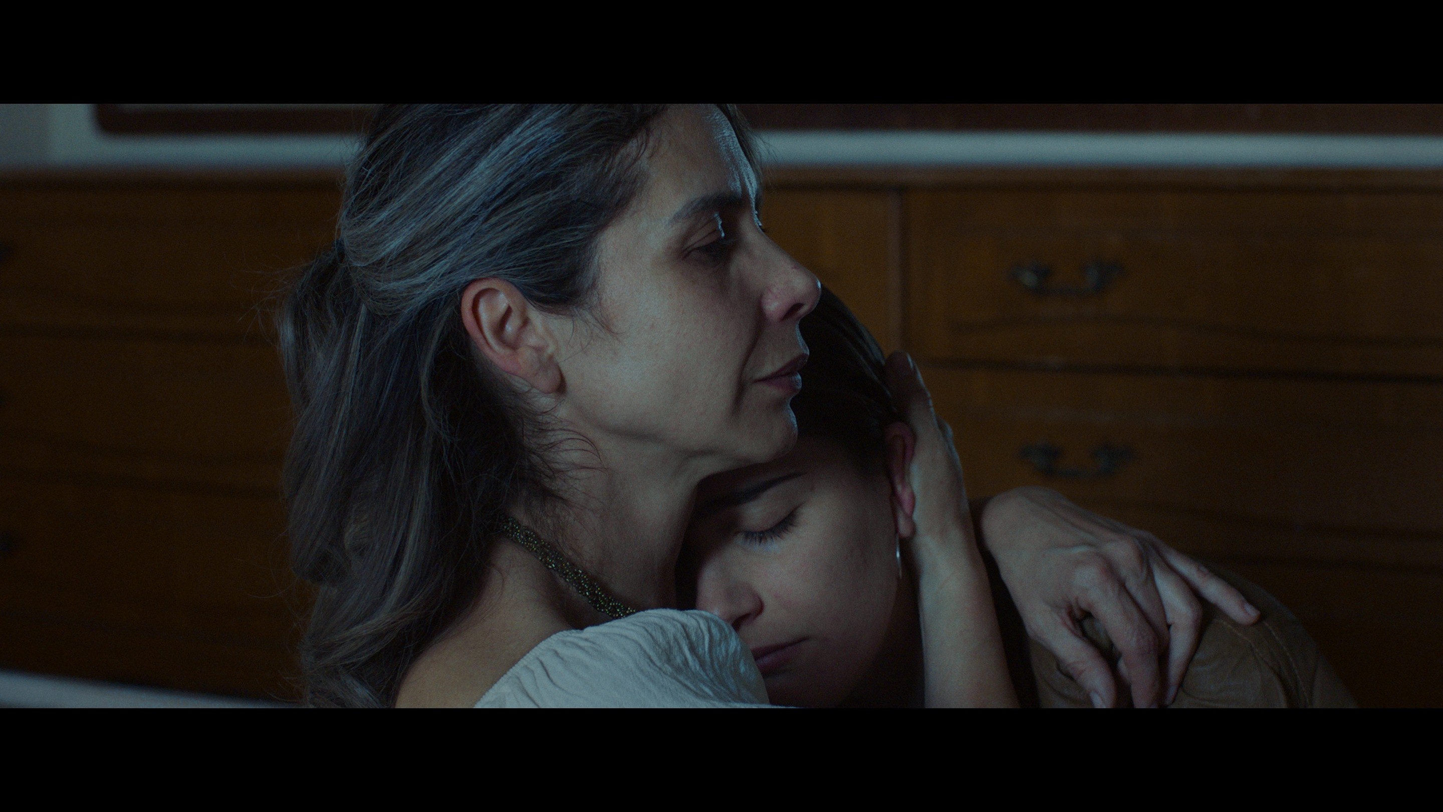 View of the French countryside through a stone villa’s open living room, with sofas and trees framing the scene