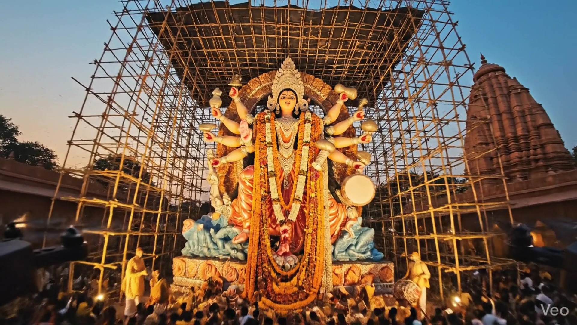 A cinematic AI-generated video by Mahendra R capturing the Durga Puja, featuring a magnificent, multi-armed idol of Goddess Durga, surrounded by devotees' worshiping with a temple spire in the background.