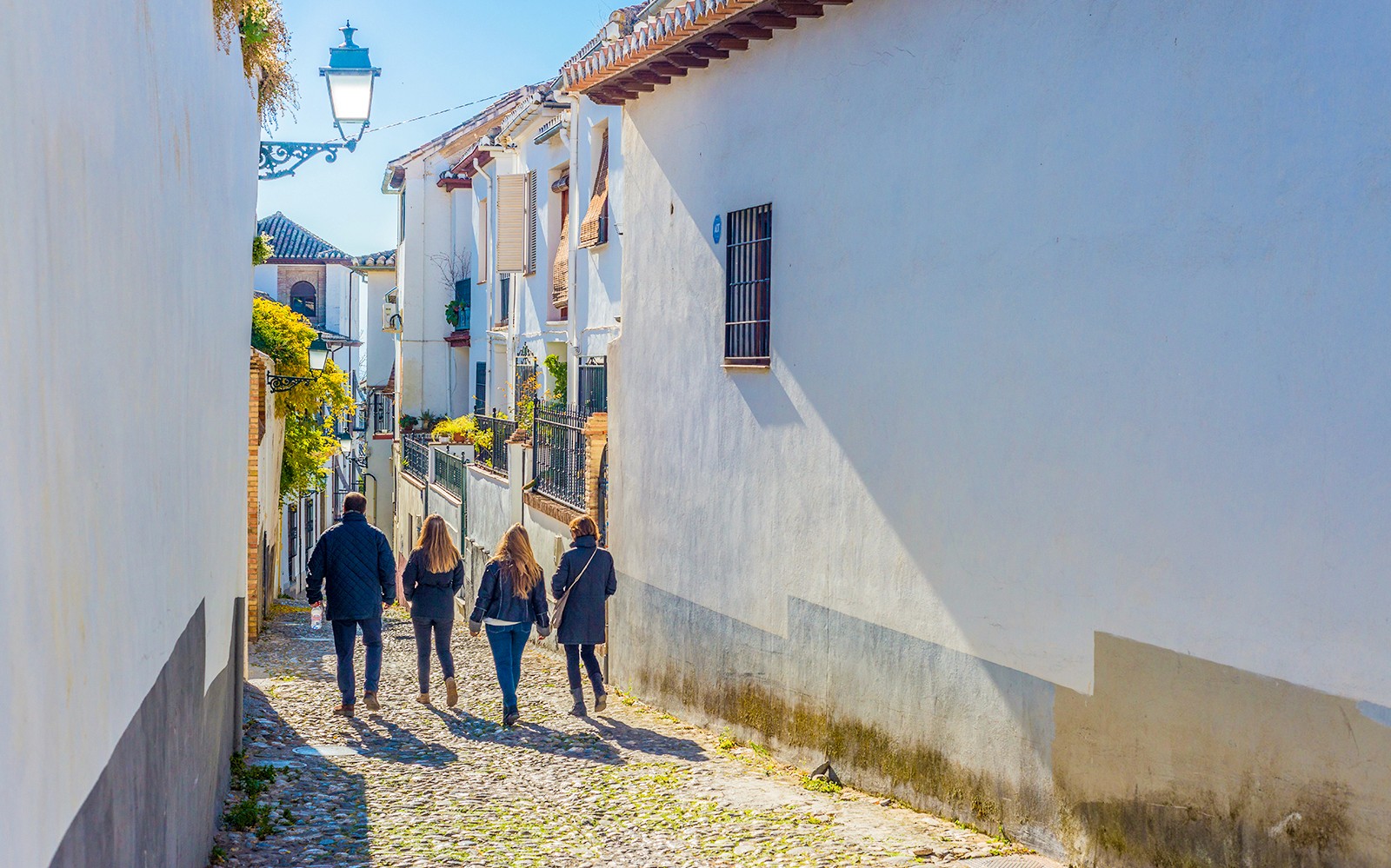 Turisti che camminano per le strette vie acciottolate dell'Albaicín, a Granada.