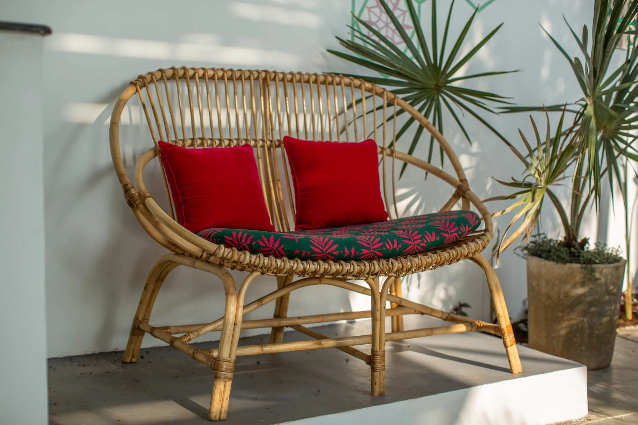Handwoven rattan loveseat with red cushions at Casa Jaali