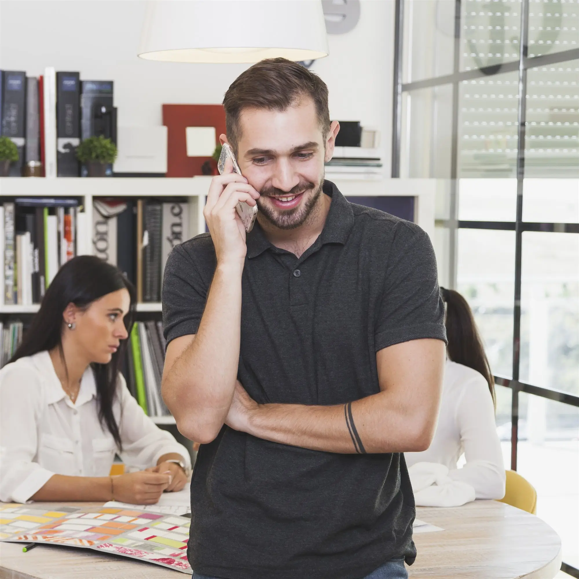 Small team at work, one colleague taking a sales call