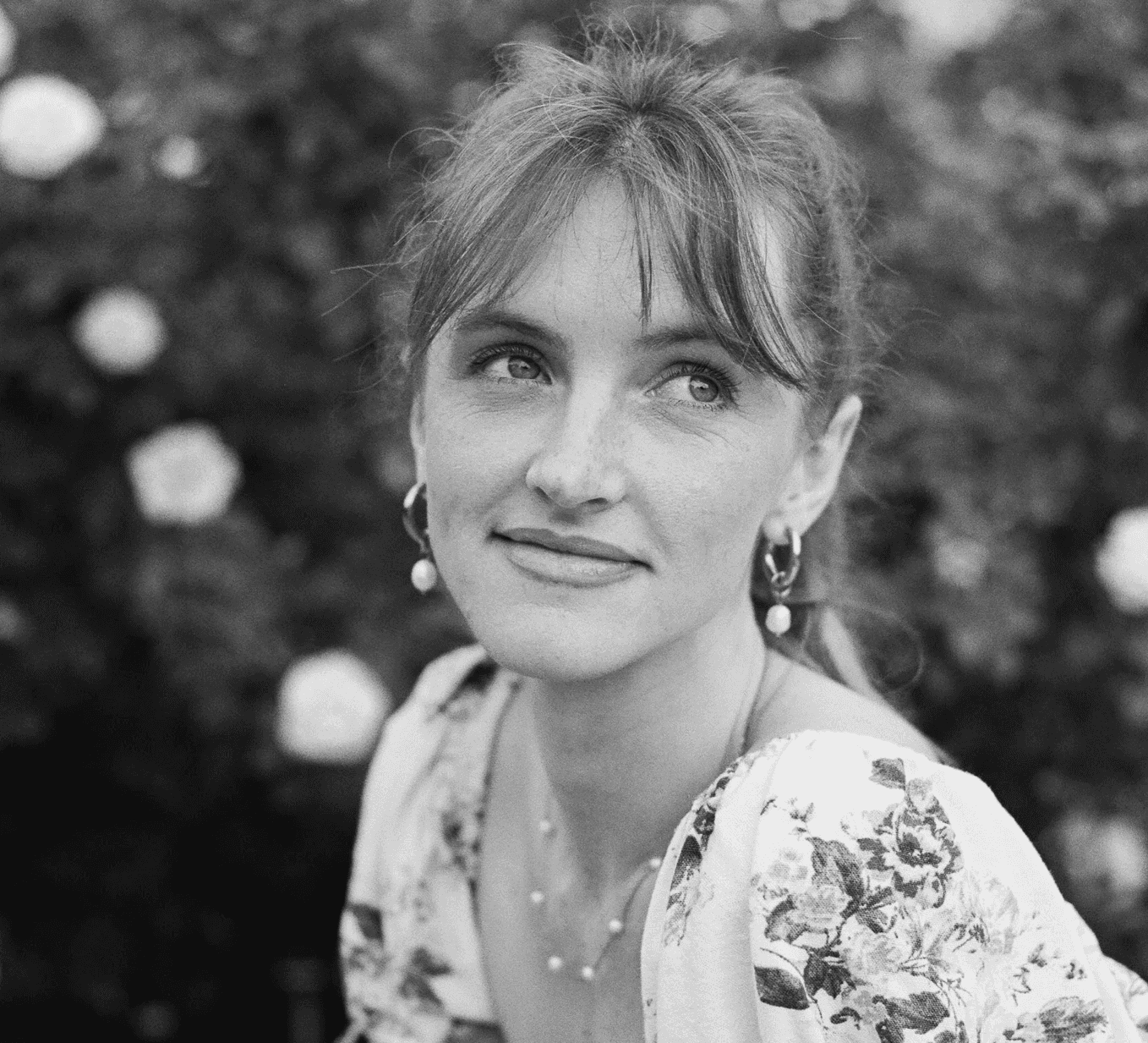 Portrait of a laughing person with curly hair wearing a white shirt