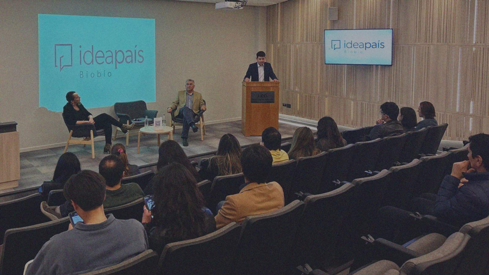 Foto del panel de conversación y asistentes de la actividad desarrollada por IdeaPaís Biobío en el Auditorio de la Clínica Ernesto Silva Bafullay de la Universidad del Desarrollo.