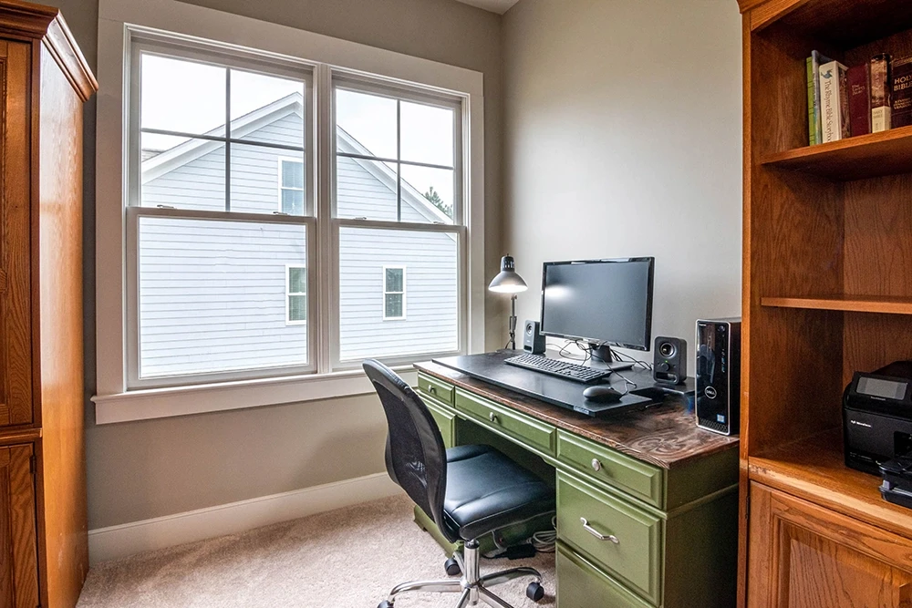Office with warm wooden furniture and an empty white window
