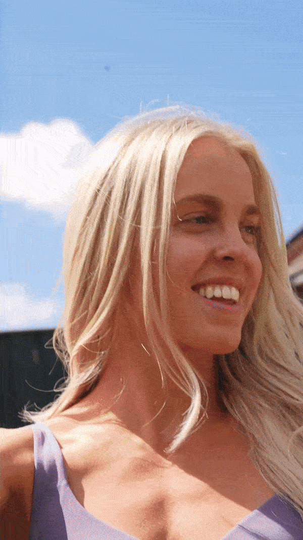 Close-up of a model holding wheat, dressed in a beige suit.