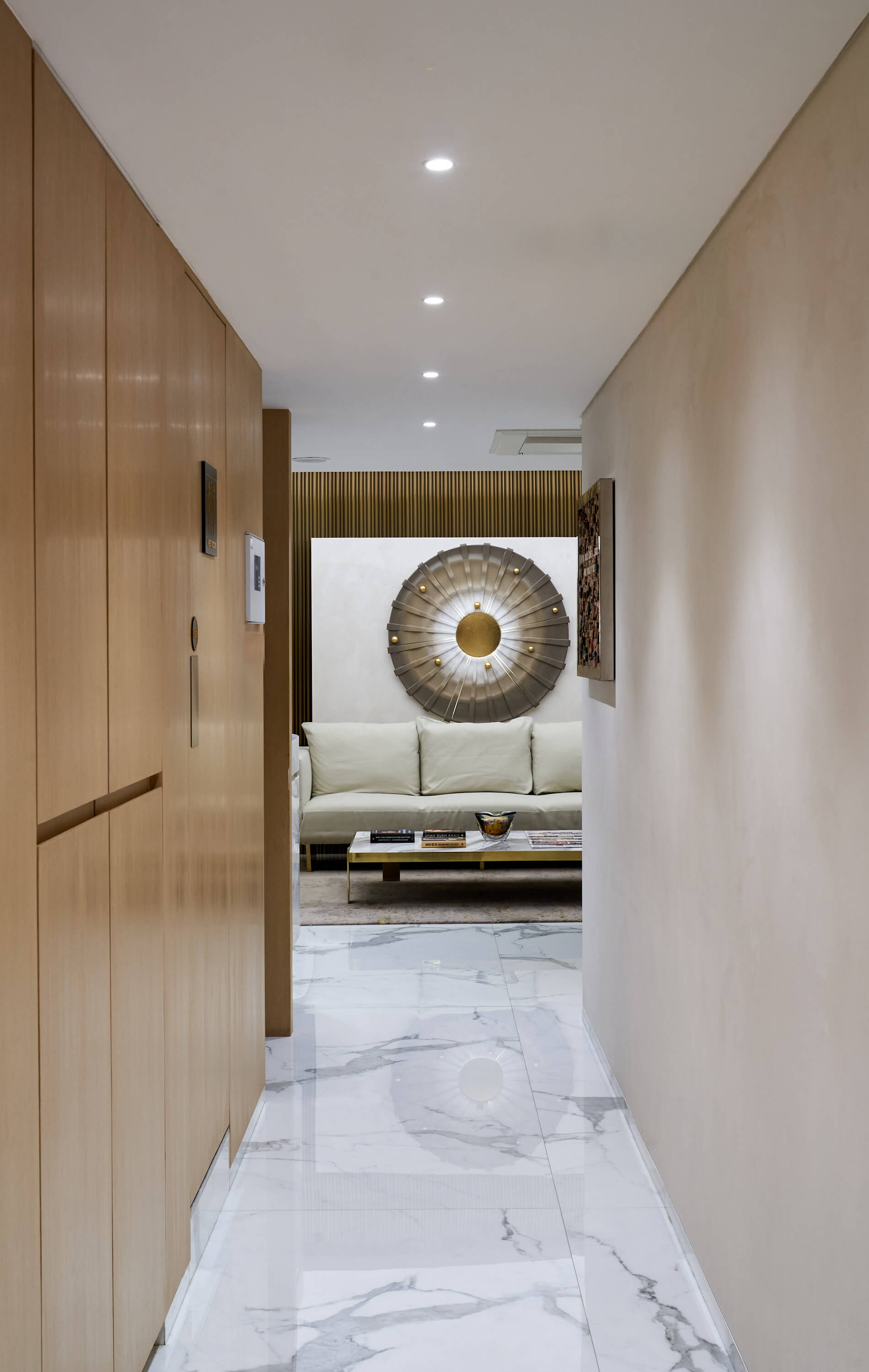Corridor view toward lounge with marble flooring and sculptural wall feature.